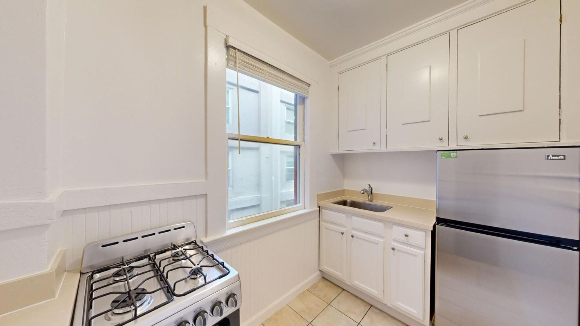 A kitchen with a stove, sink, and cabinets.