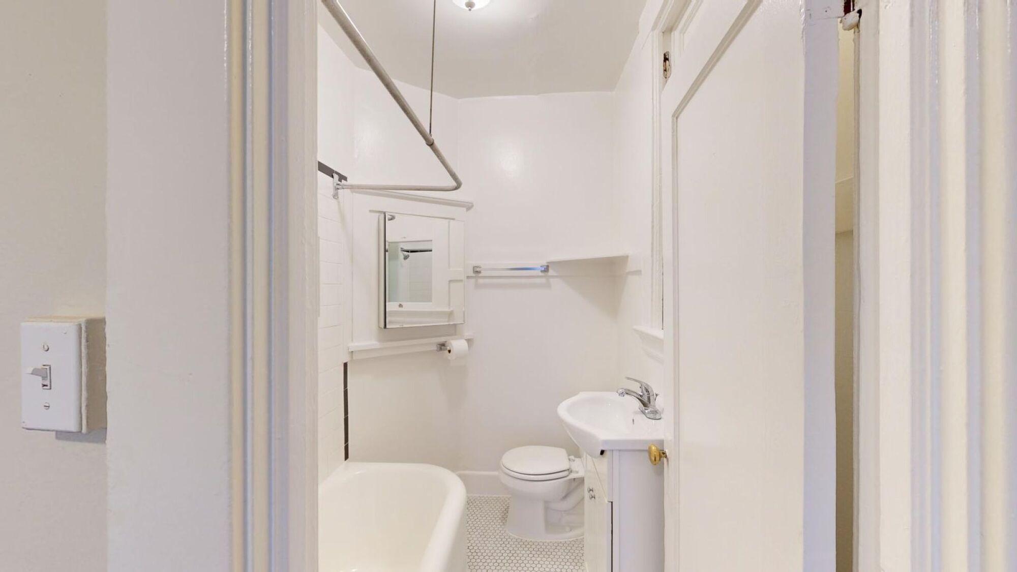 A white toilet with a white sink and a white chair in a bathroom.