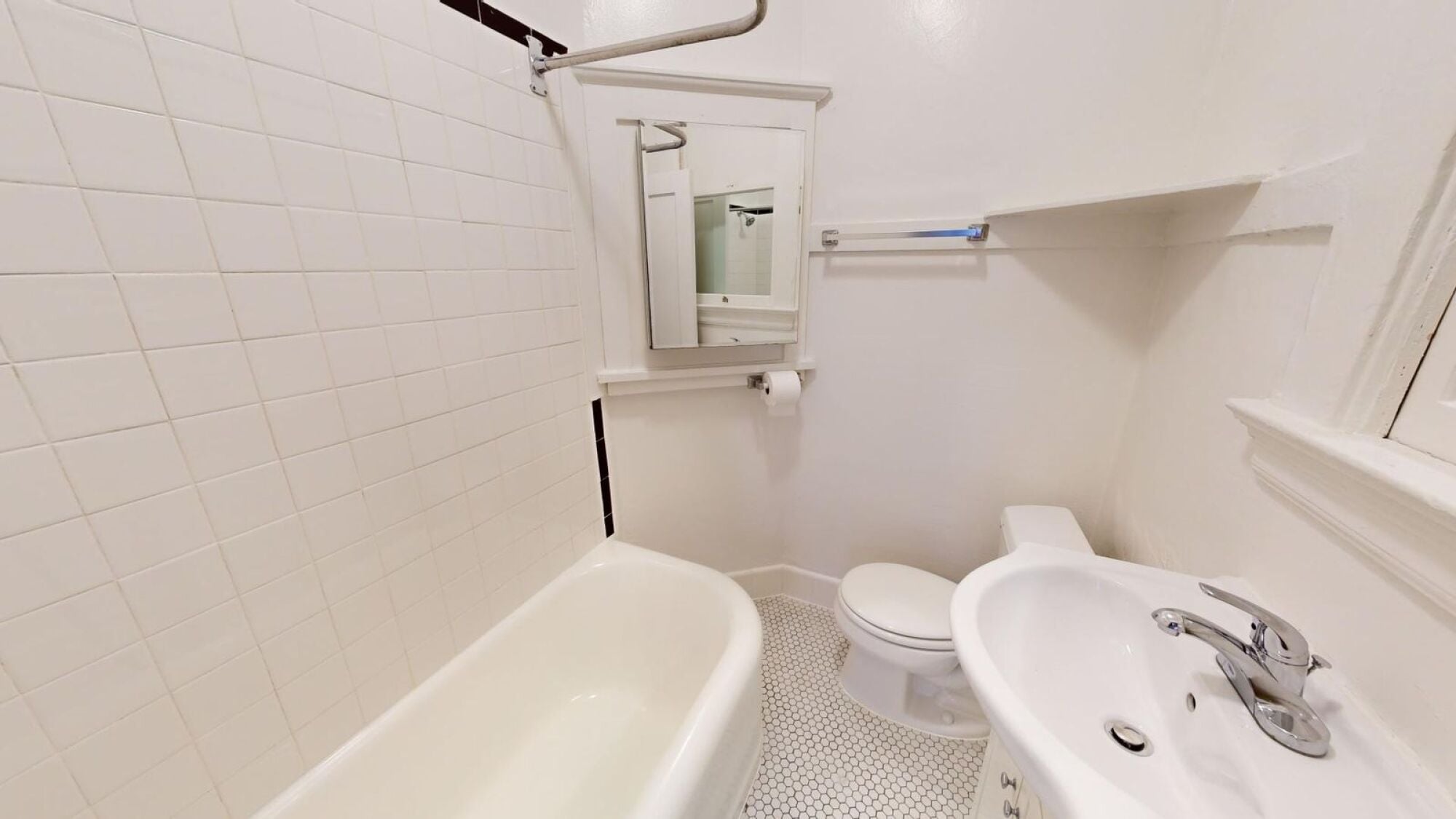 A white bathroom with a toilet, sink, and bathtub.