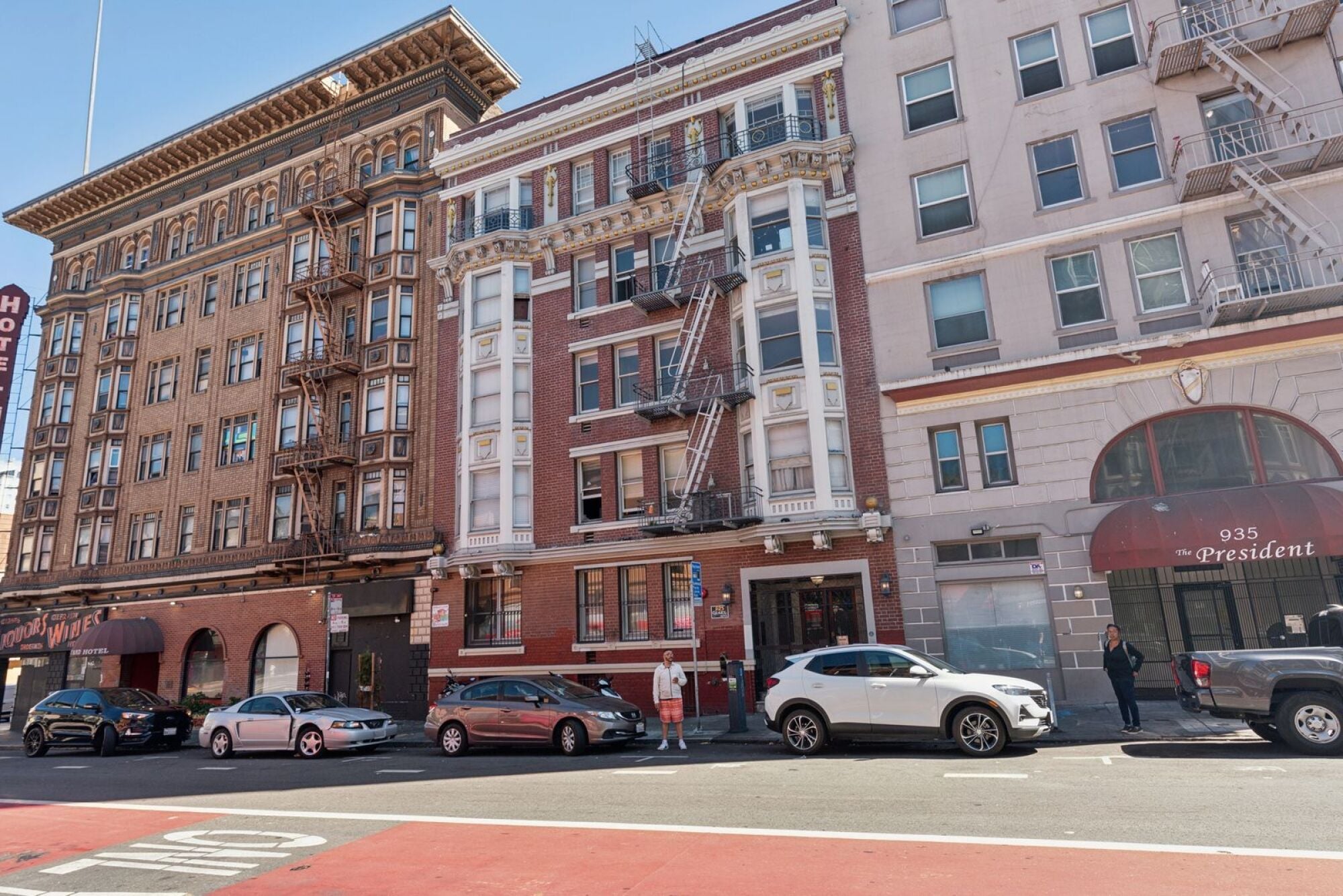 A white car is parked in front of a red building.