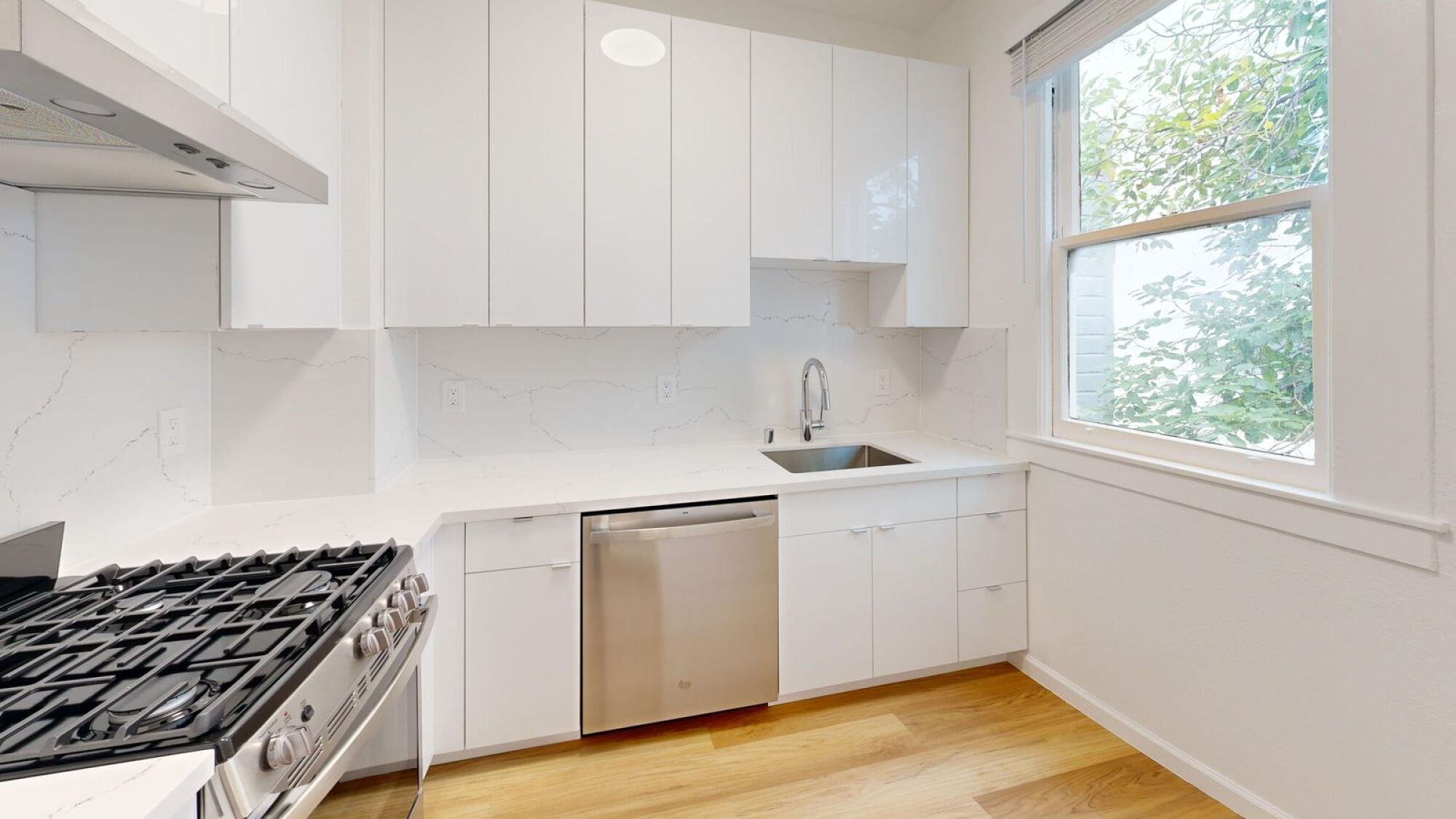 A modern kitchen with white cabinets and a black stove top.