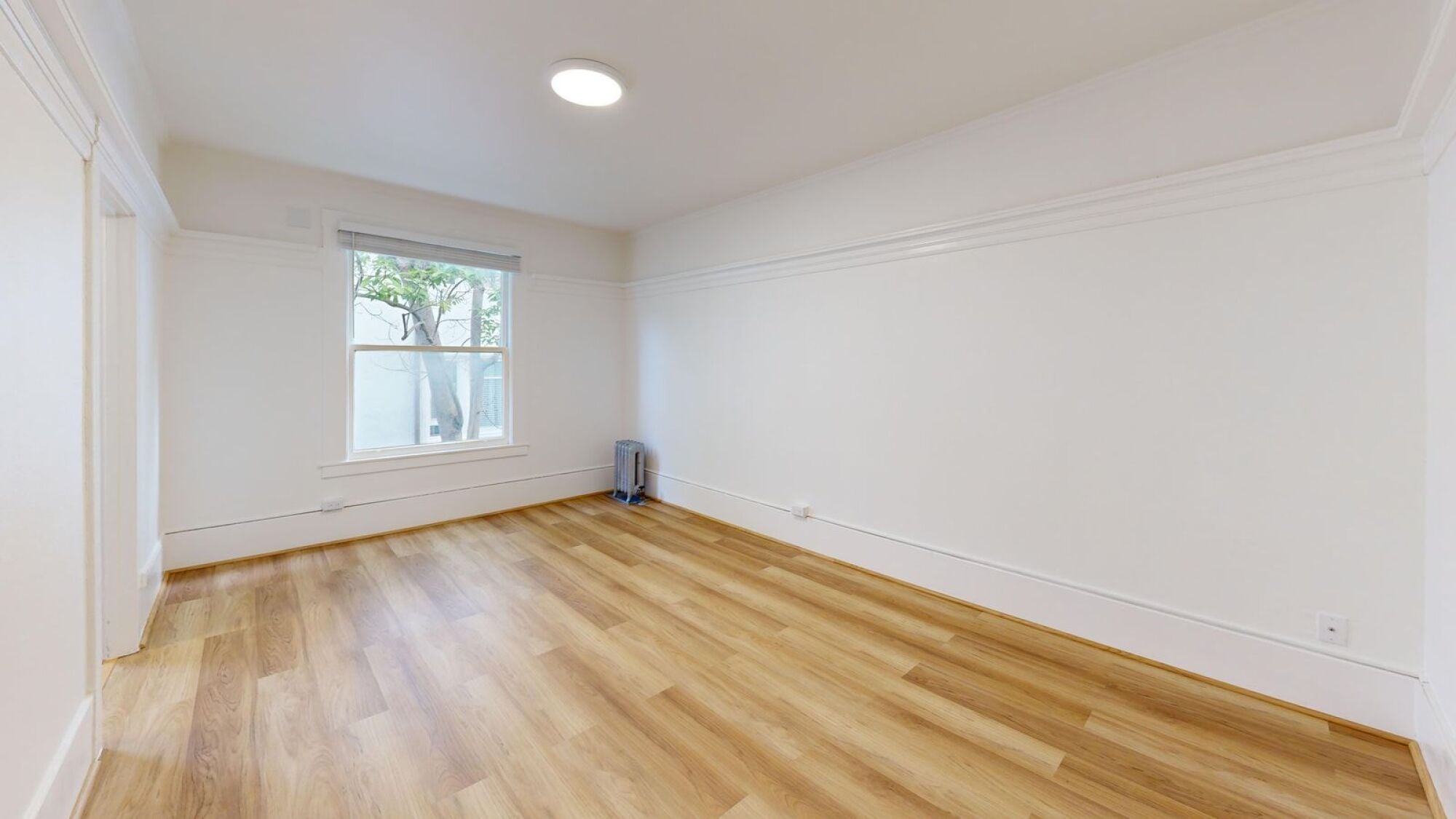 A room with wooden flooring and a window.