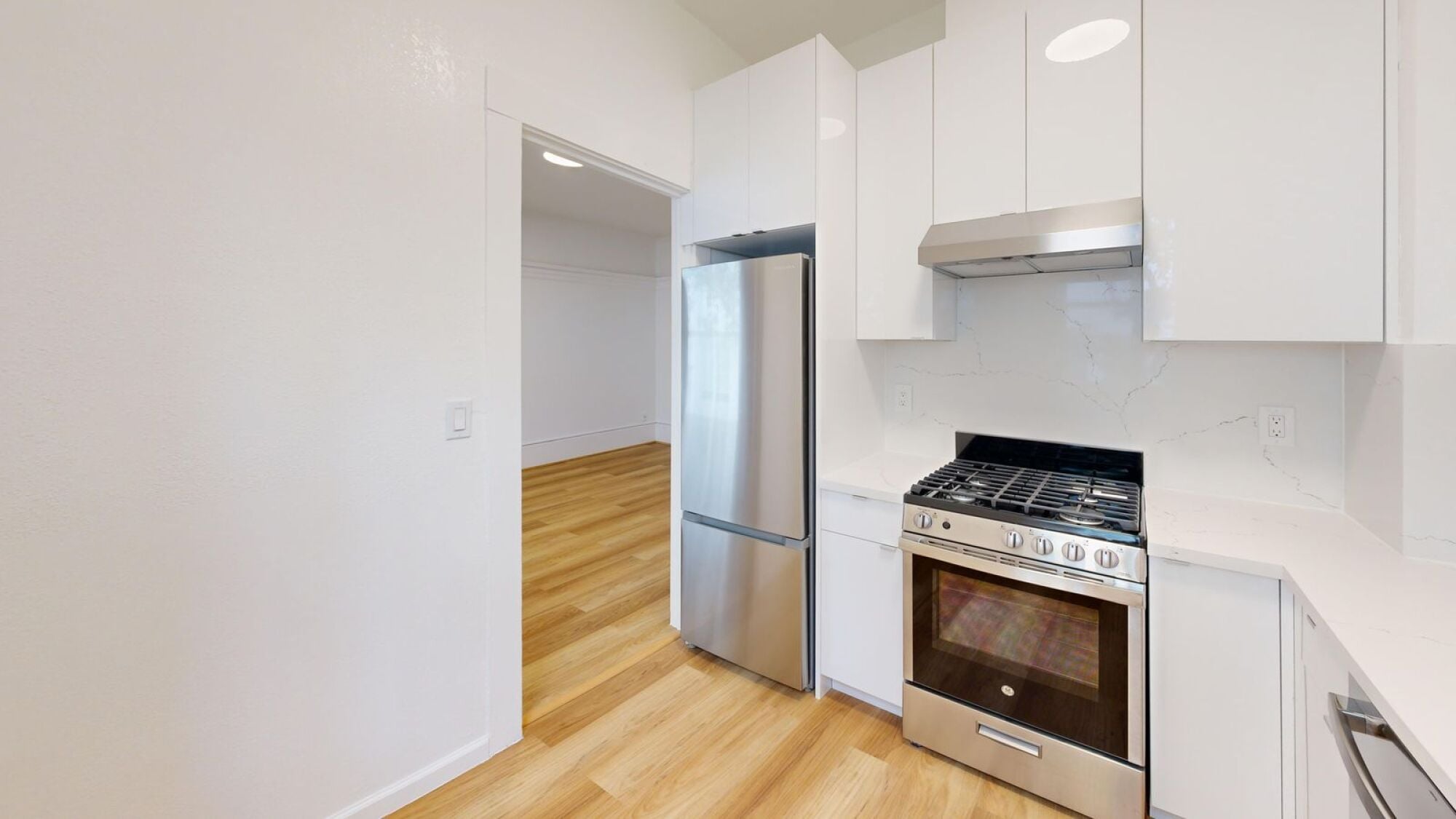 A kitchen with a stainless steel refrigerator and a stove top oven.
