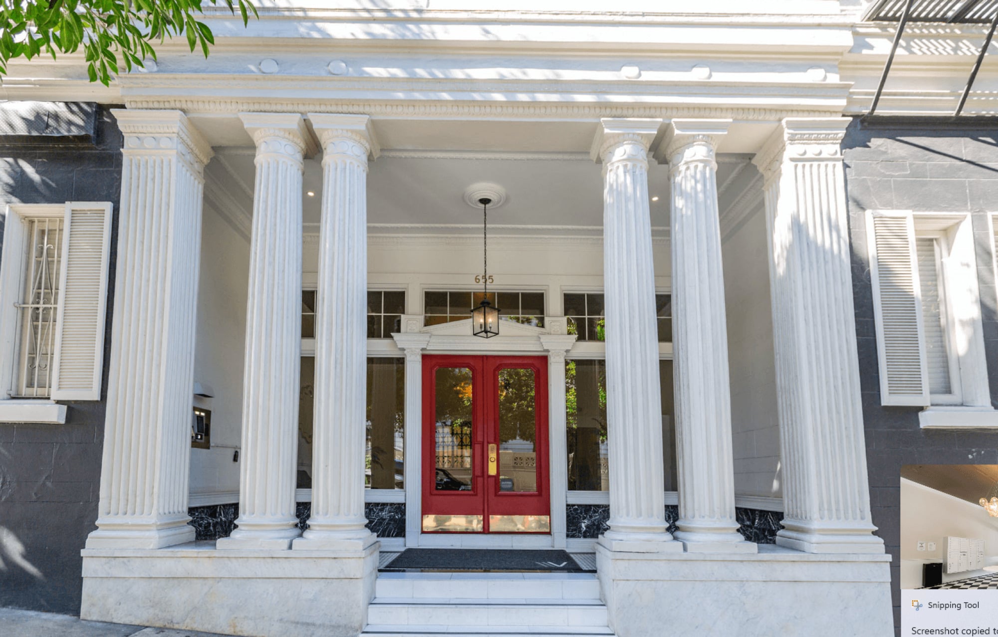 A white building with a red door and pillars.