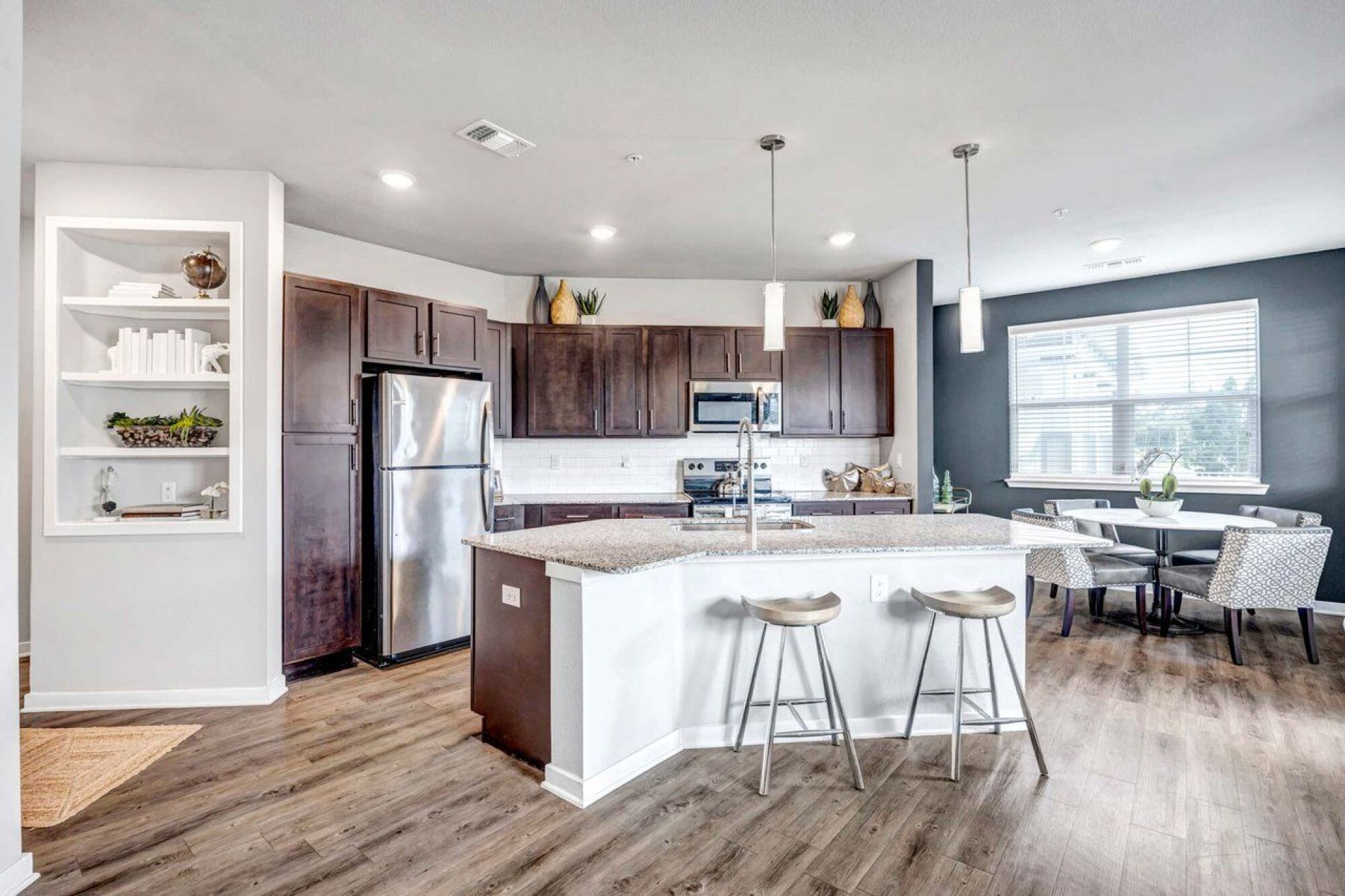 Modern kitchen with dark wood cabinets, stainless steel appliances, island, and two bar stools at Luminary at 95 apartments.