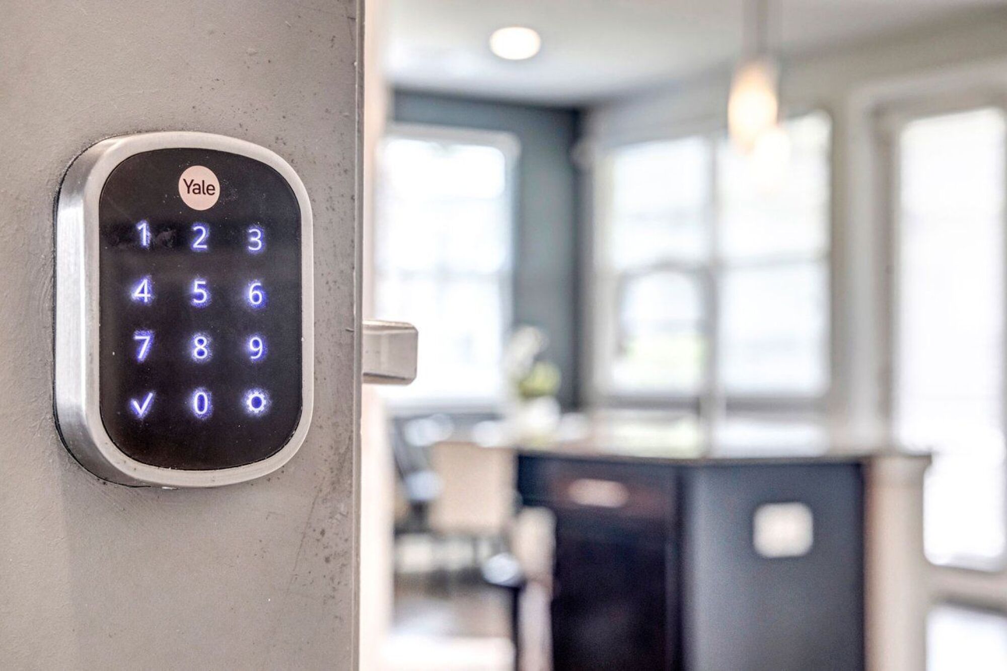 Close-up of a digital Yale door lock keypad with glowing numbers, in a modern, bright home interior at Luminary at 95.