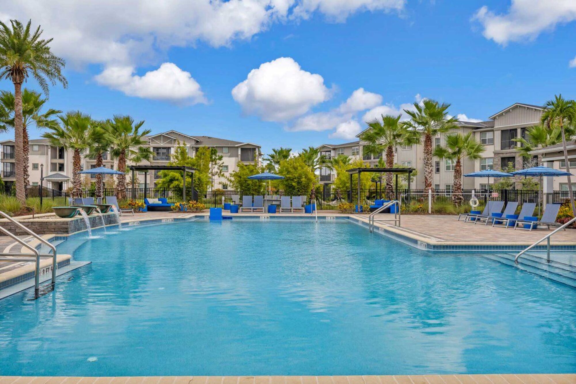 A pool with palm trees and a building at Luminary at 95.