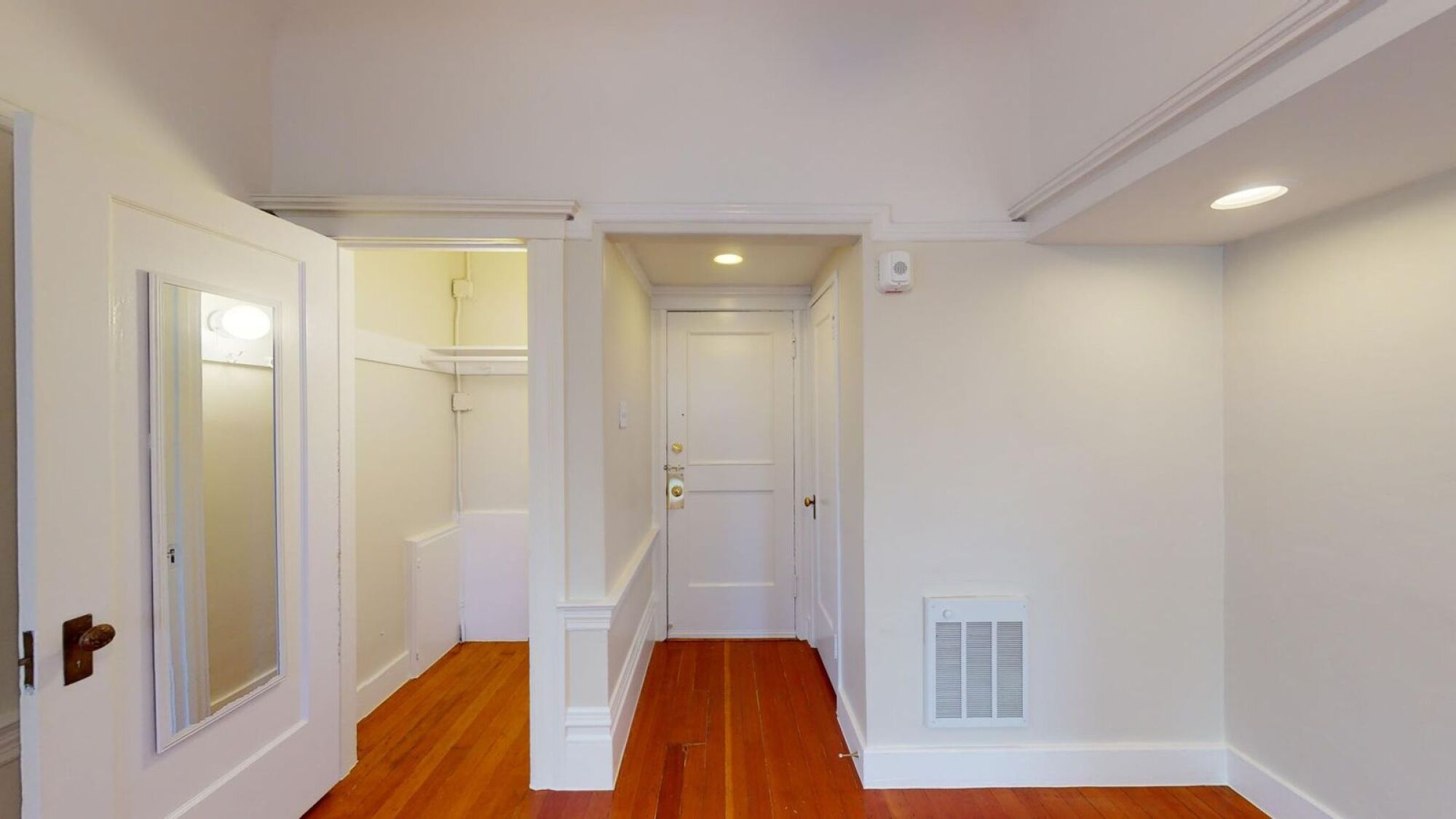 A hallway with a wooden floor and white walls.