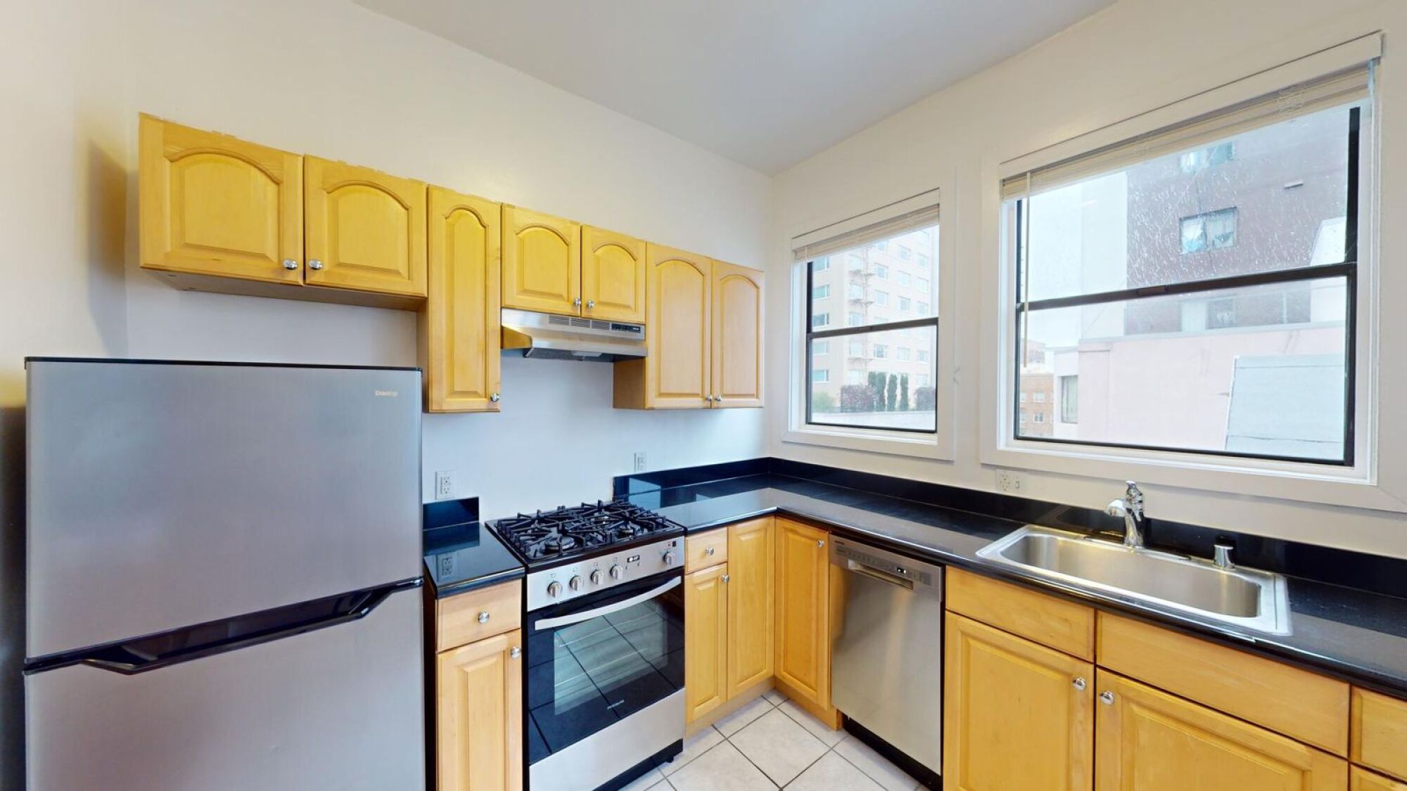 A kitchen with wooden cabinets and a stainless steel refrigerator.