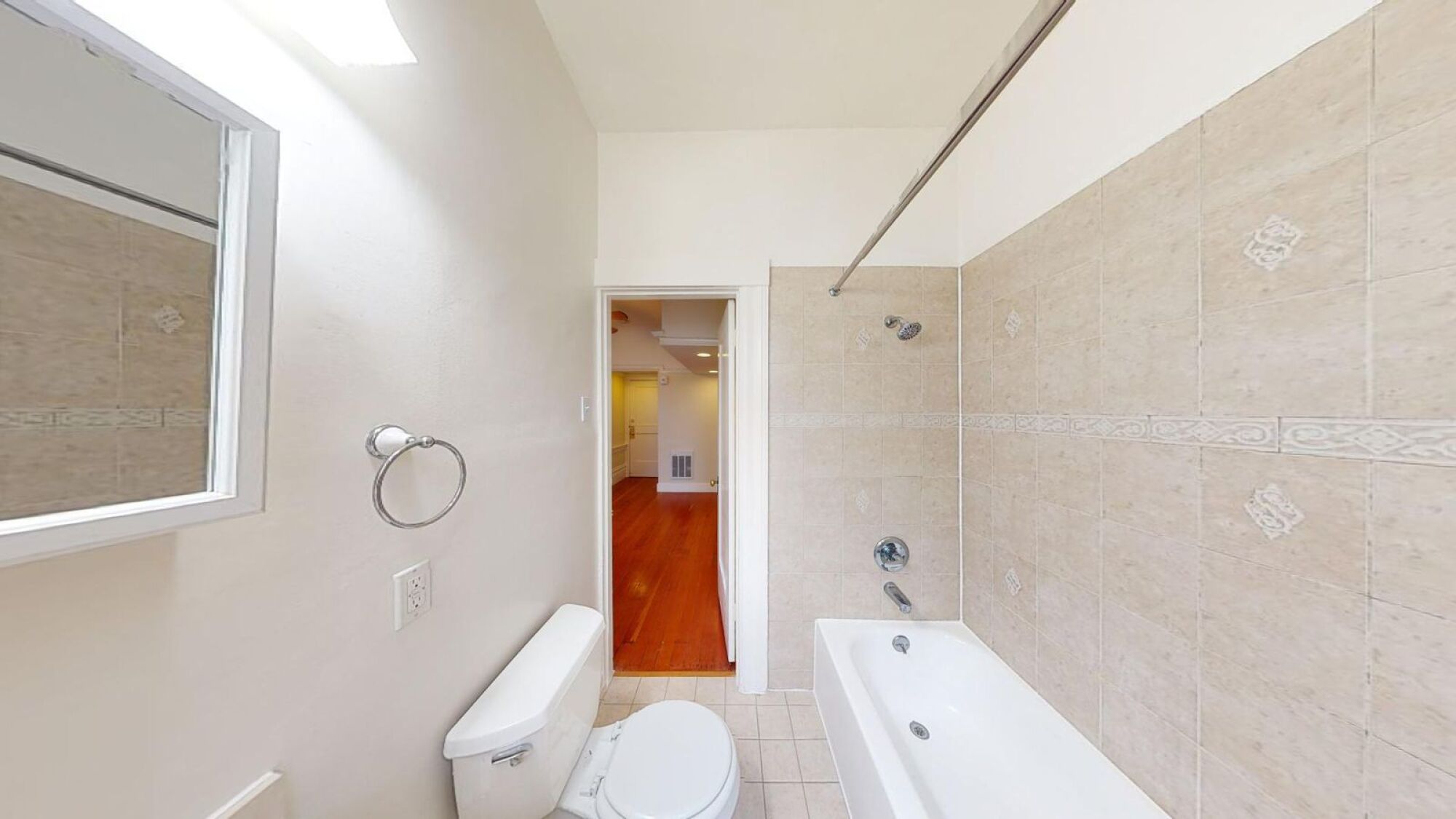 A bathroom with a toilet, tub, and mirror.