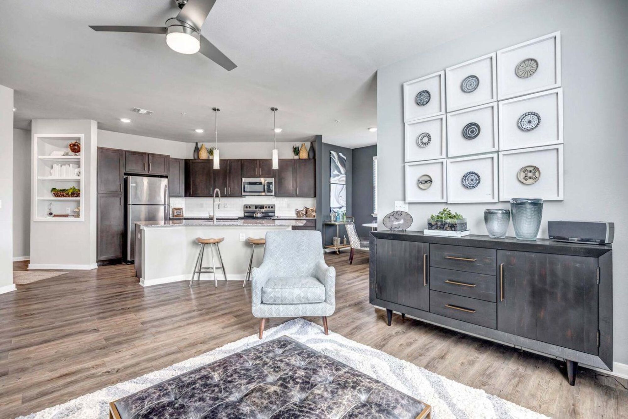 Modern open-concept kitchen and living area with stylish decor, light wood floors, and contemporary furniture at Luminary at 95 apartments.