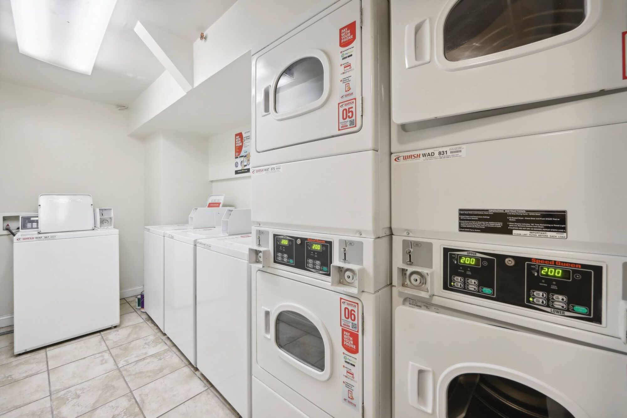 A row of white front load washing machines in a laundromat.