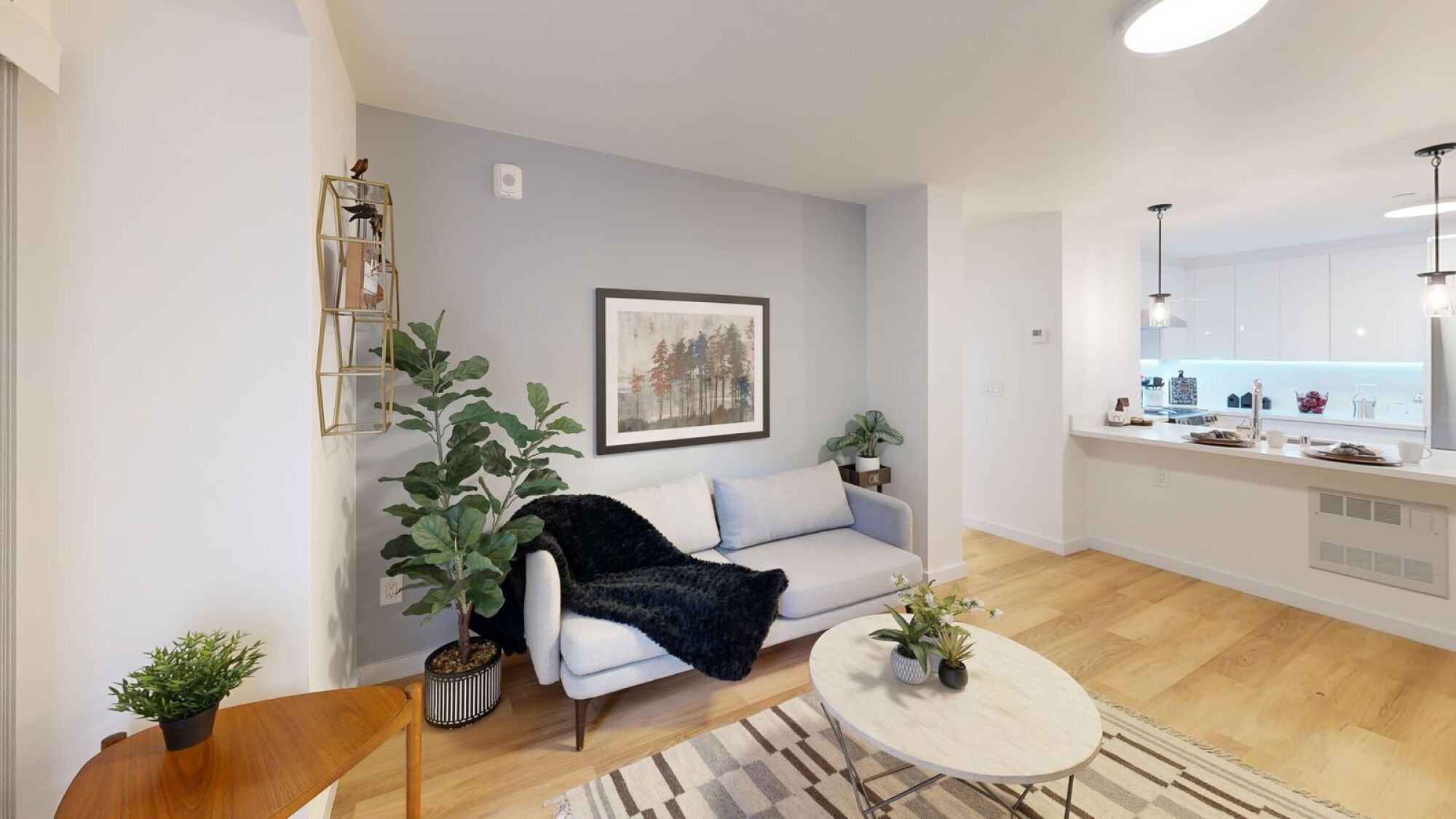 A living room with a white couch, a coffee table, and a painting on the wall.