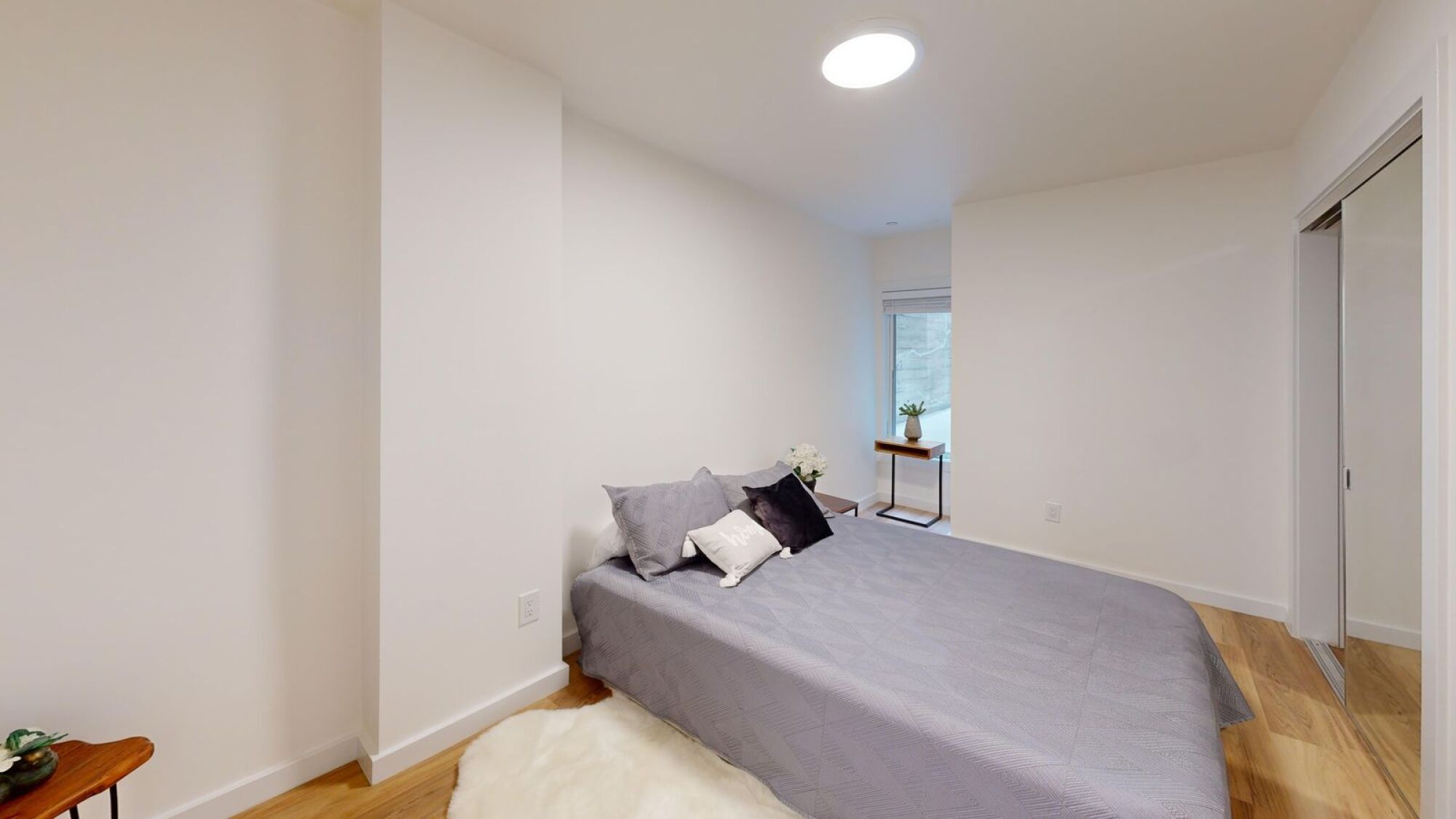 A bedroom with a bed, pillows, and a window.