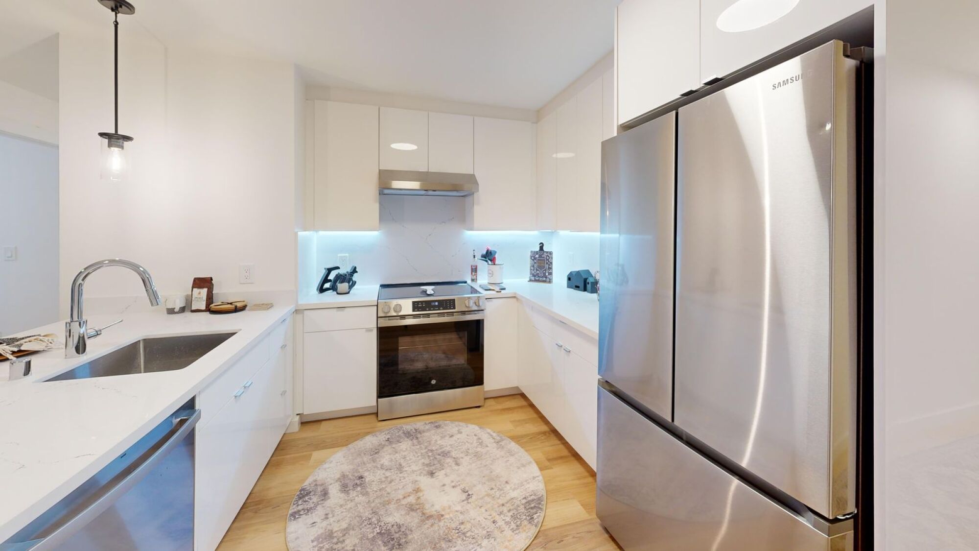 A modern kitchen with a stainless steel refrigerator and a white countertop.
