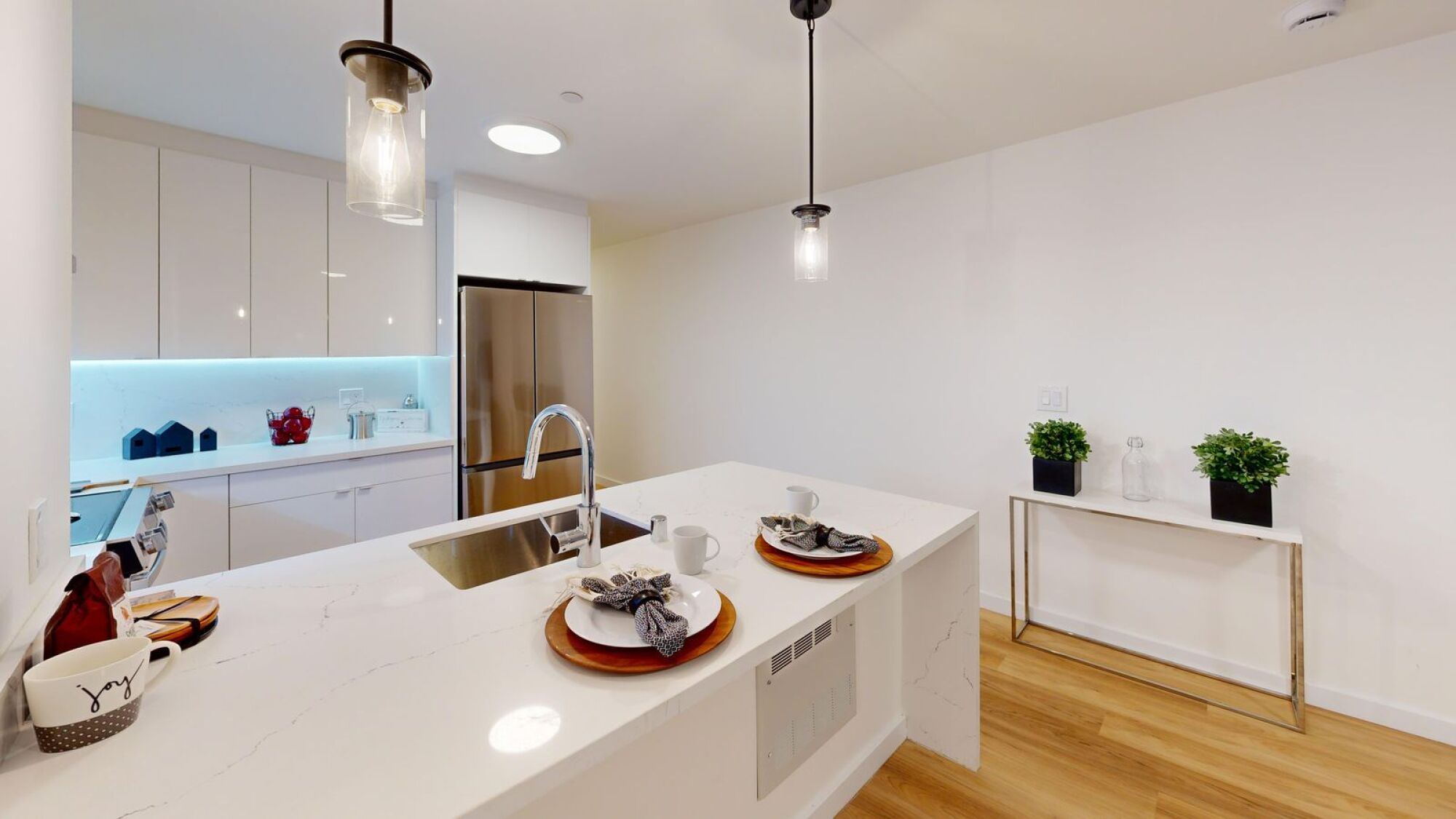 A modern kitchen with a white countertop and a wooden floor.