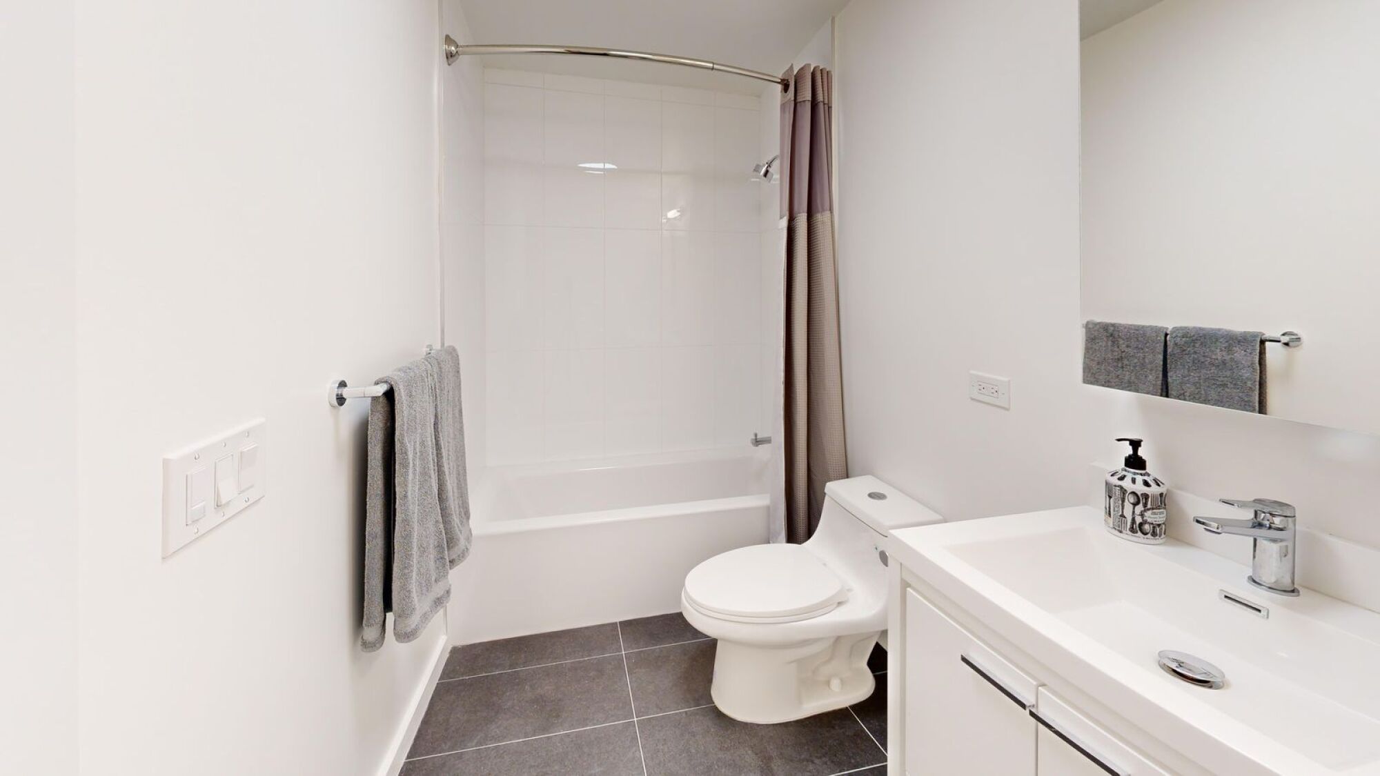 A white toilet sits in a bathroom next to a sink.