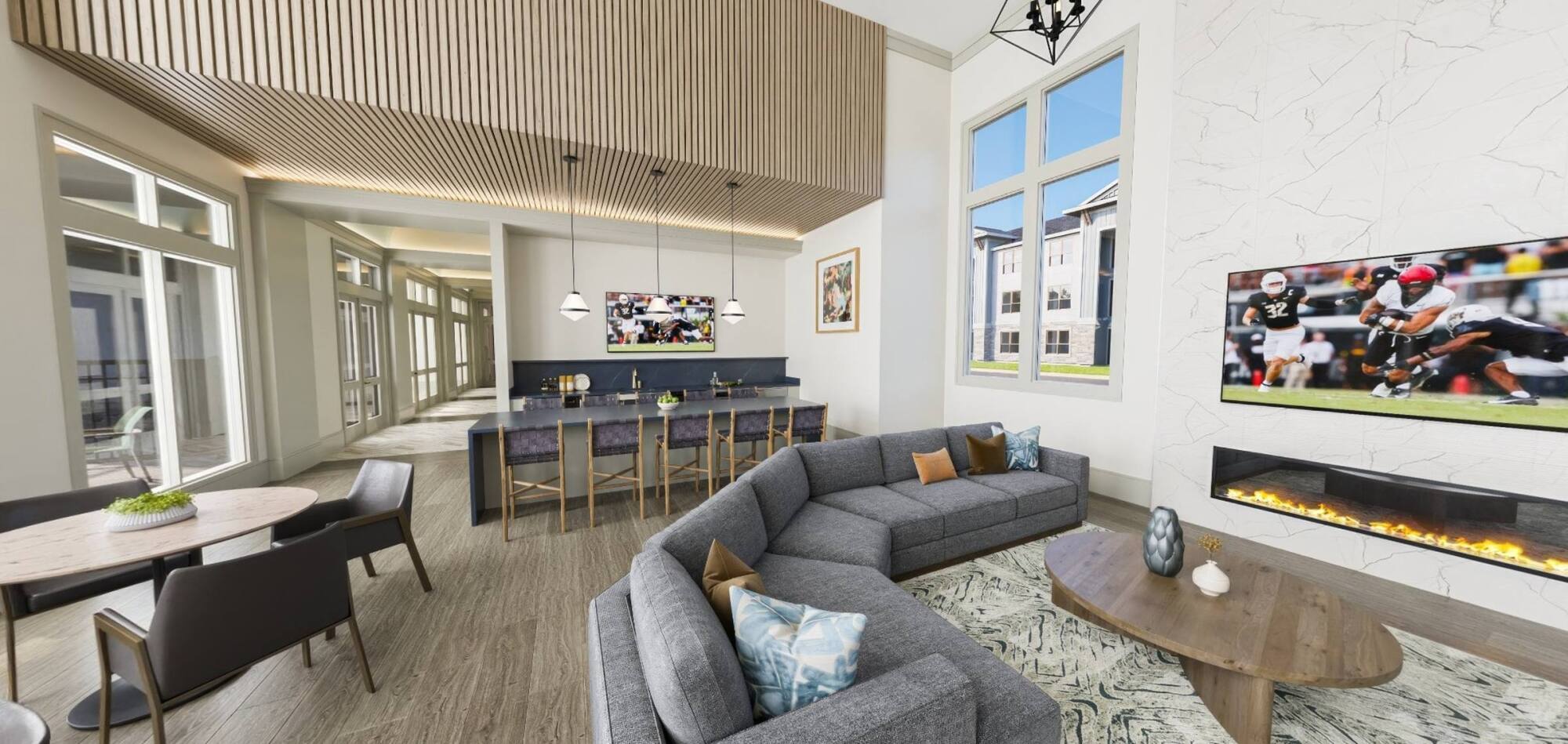 Modern lounge with gray sectional sofa, wall-mounted TV, fireplace, dining table, and large windows.