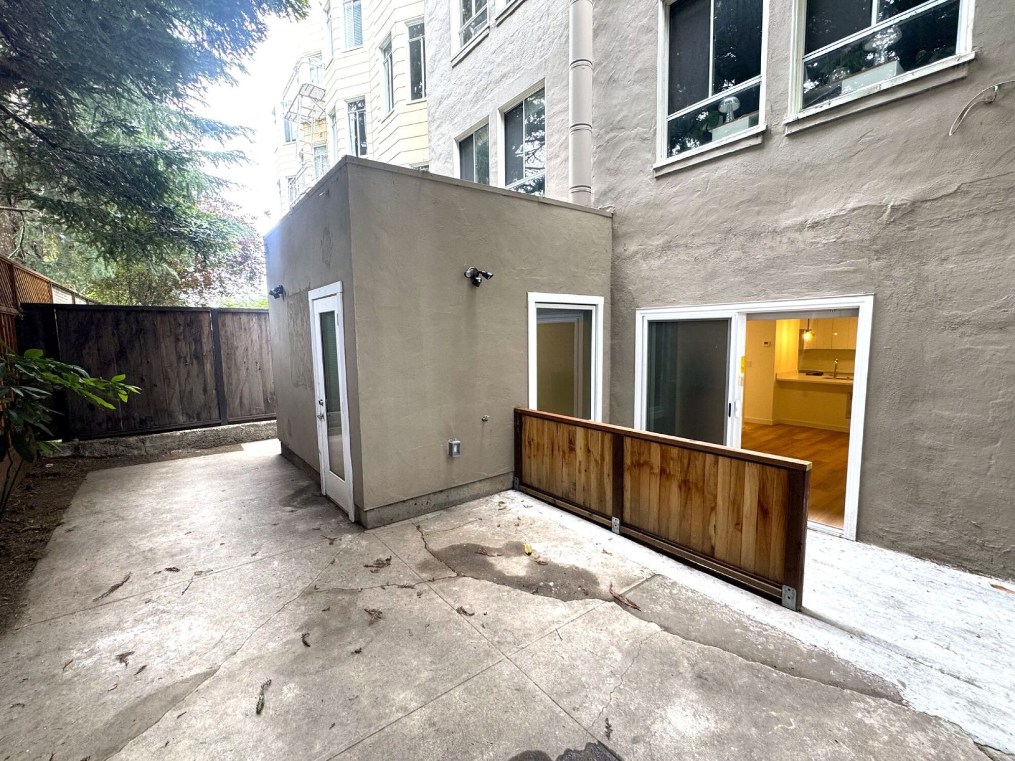 A concrete building with a wooden fence in front of a grey building.