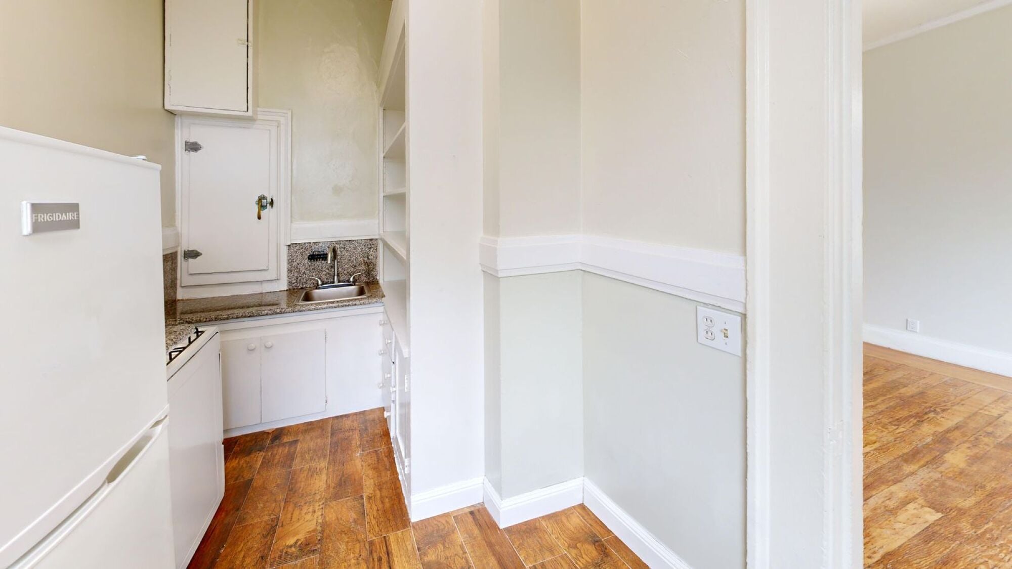 A kitchen with white cabinets and a white fridge.