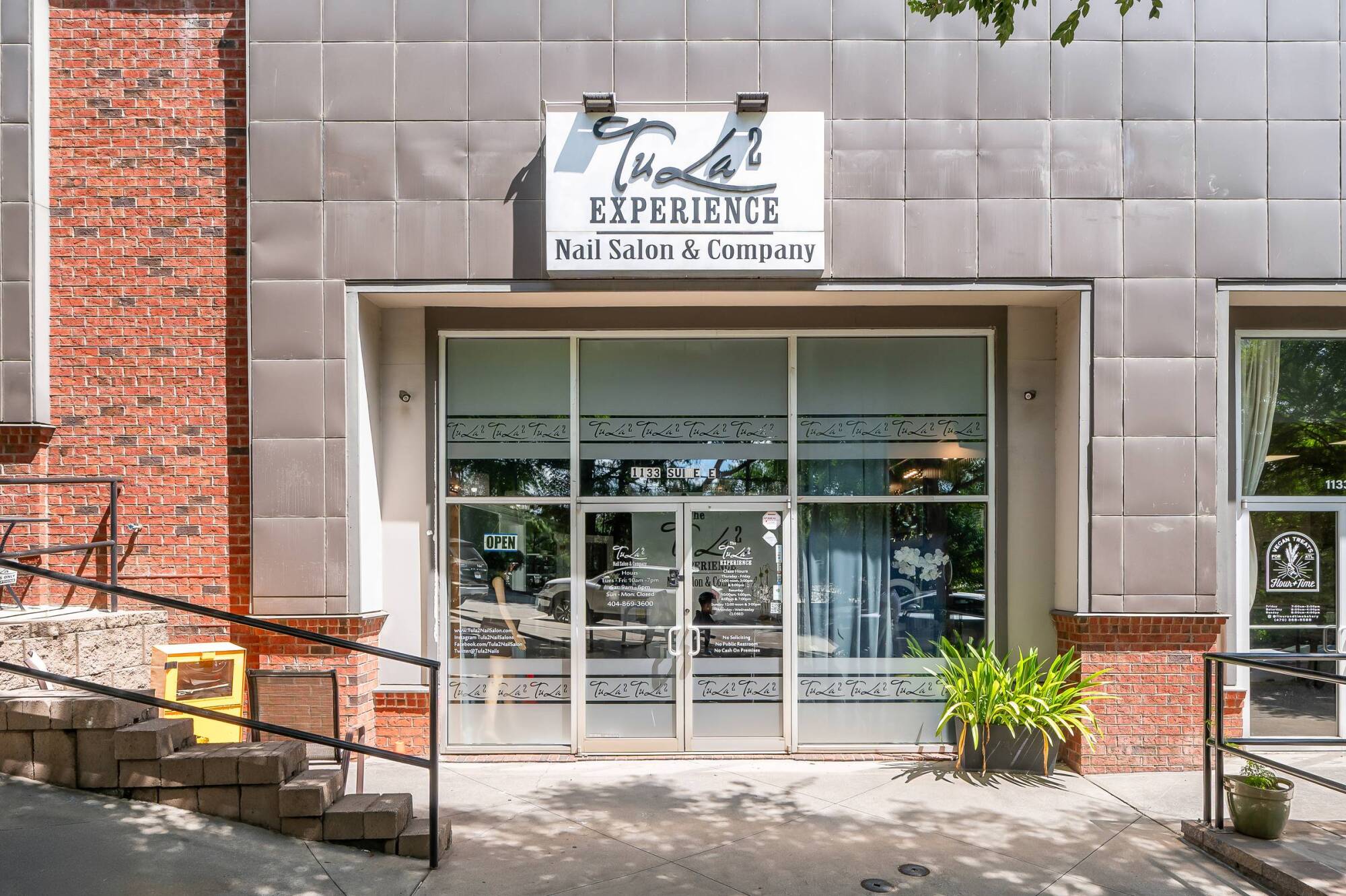 Nail salon storefront with large windows, a sign reading "Nail Experience," and potted plants by the entrance.