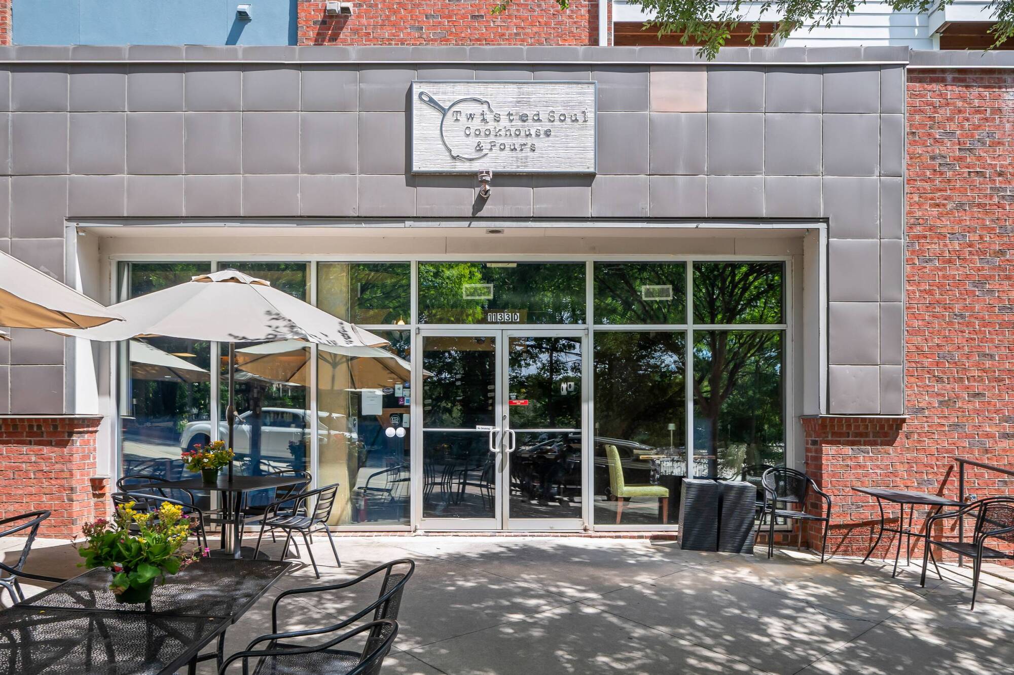 Exterior of Twisted Soul Cookhouse & Pours with outdoor seating and glass doors reflecting trees.