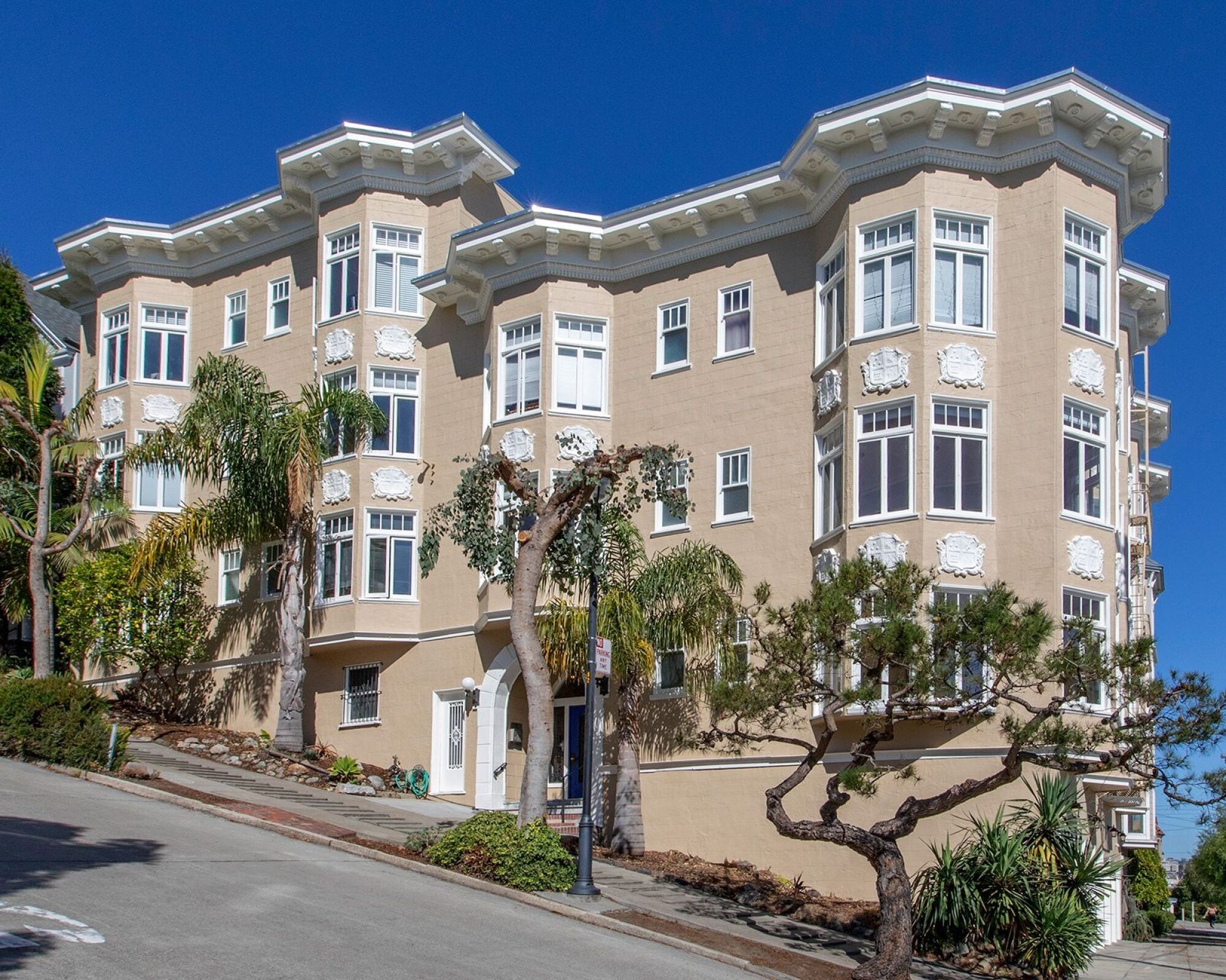 A large beige building with white trim and a balcony on the second floor.