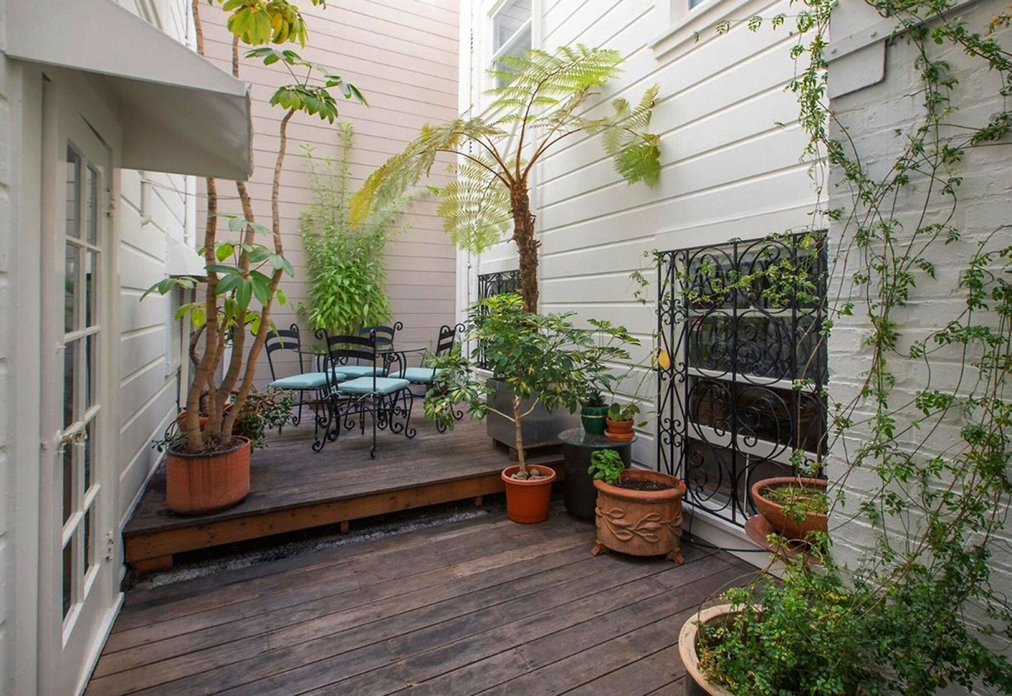 A patio with a table and chairs surrounded by potted plants.