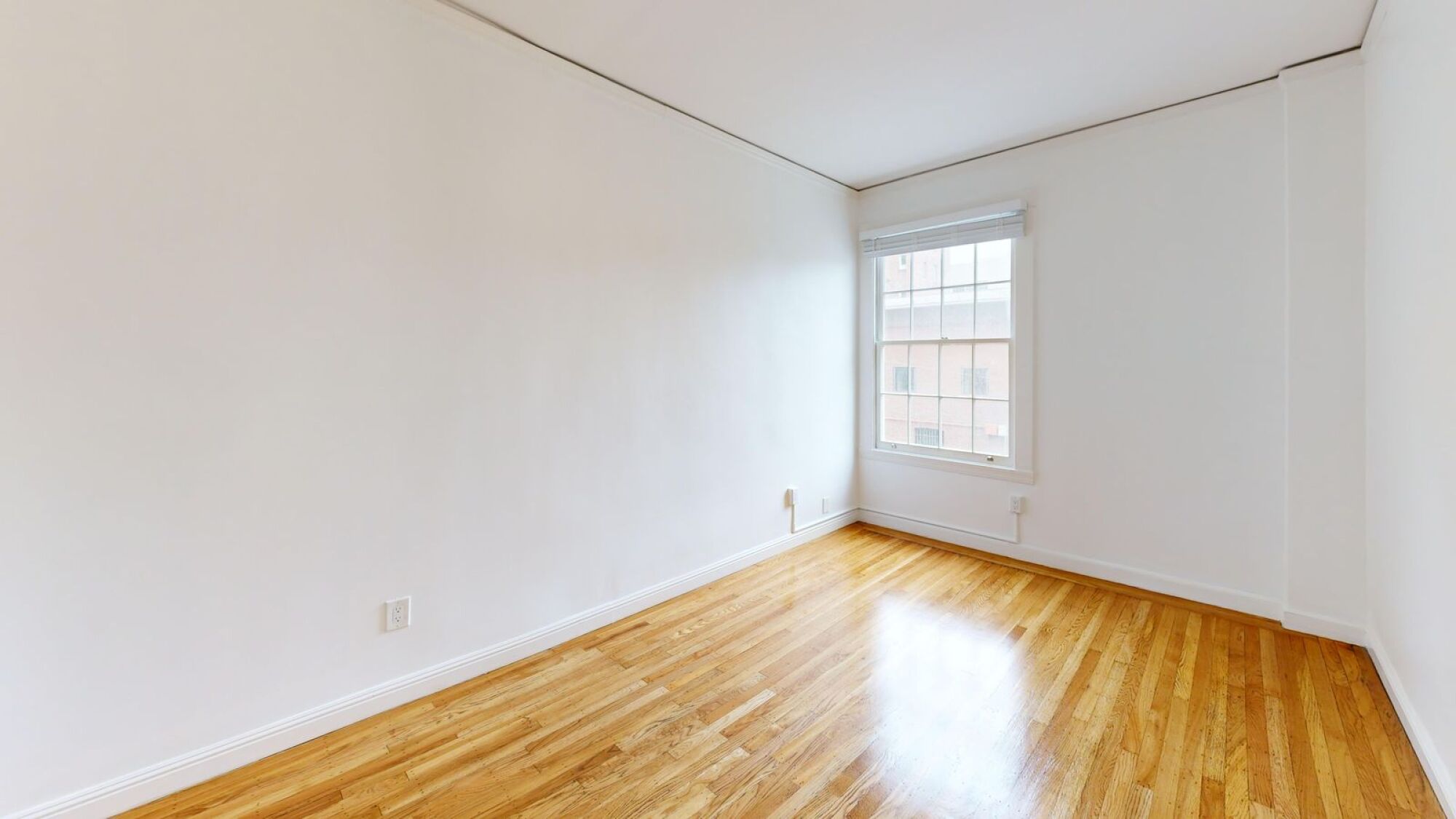 A room with wooden flooring and a window.
