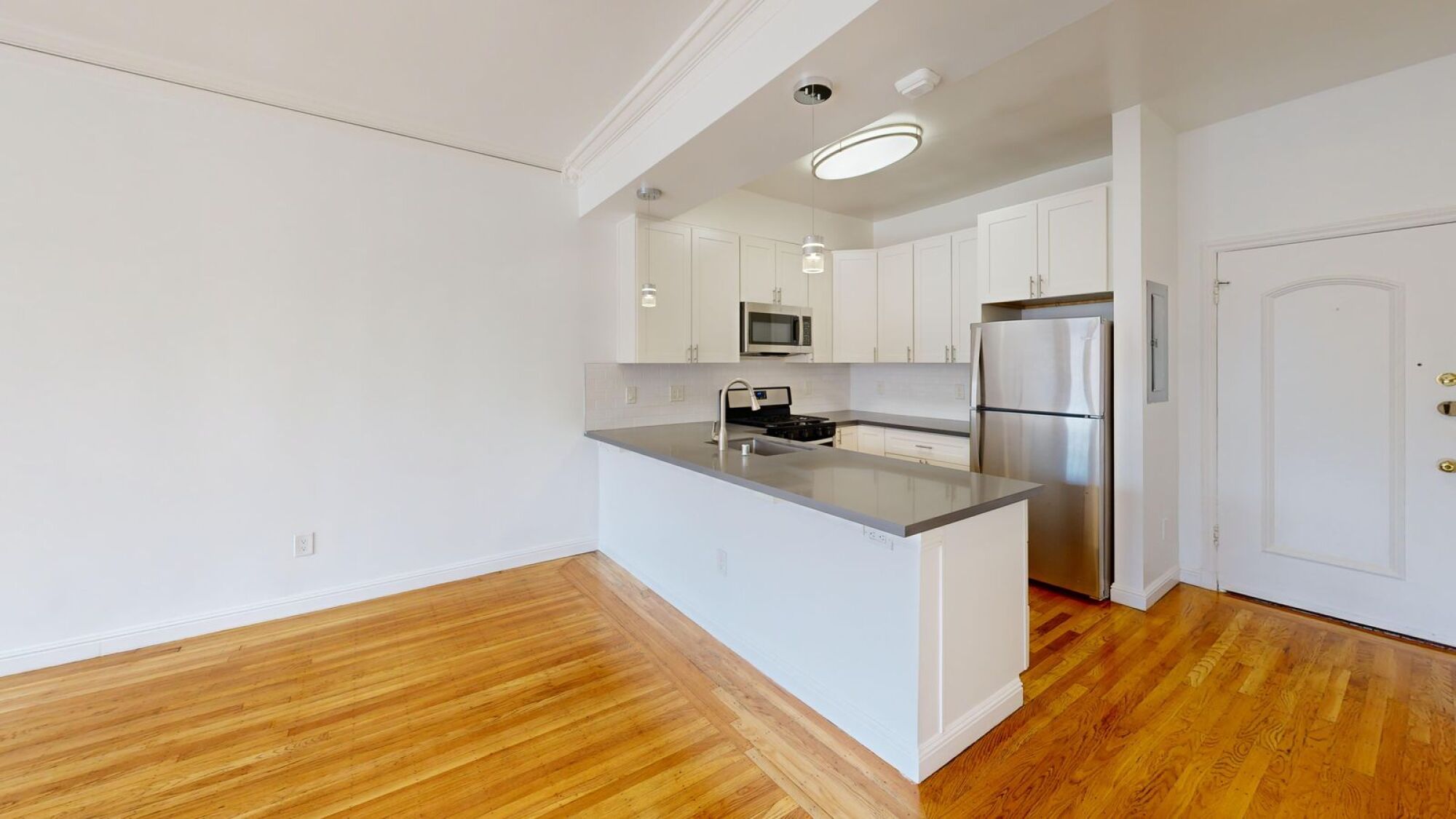 A kitchen with white cabinets and a wooden floor.