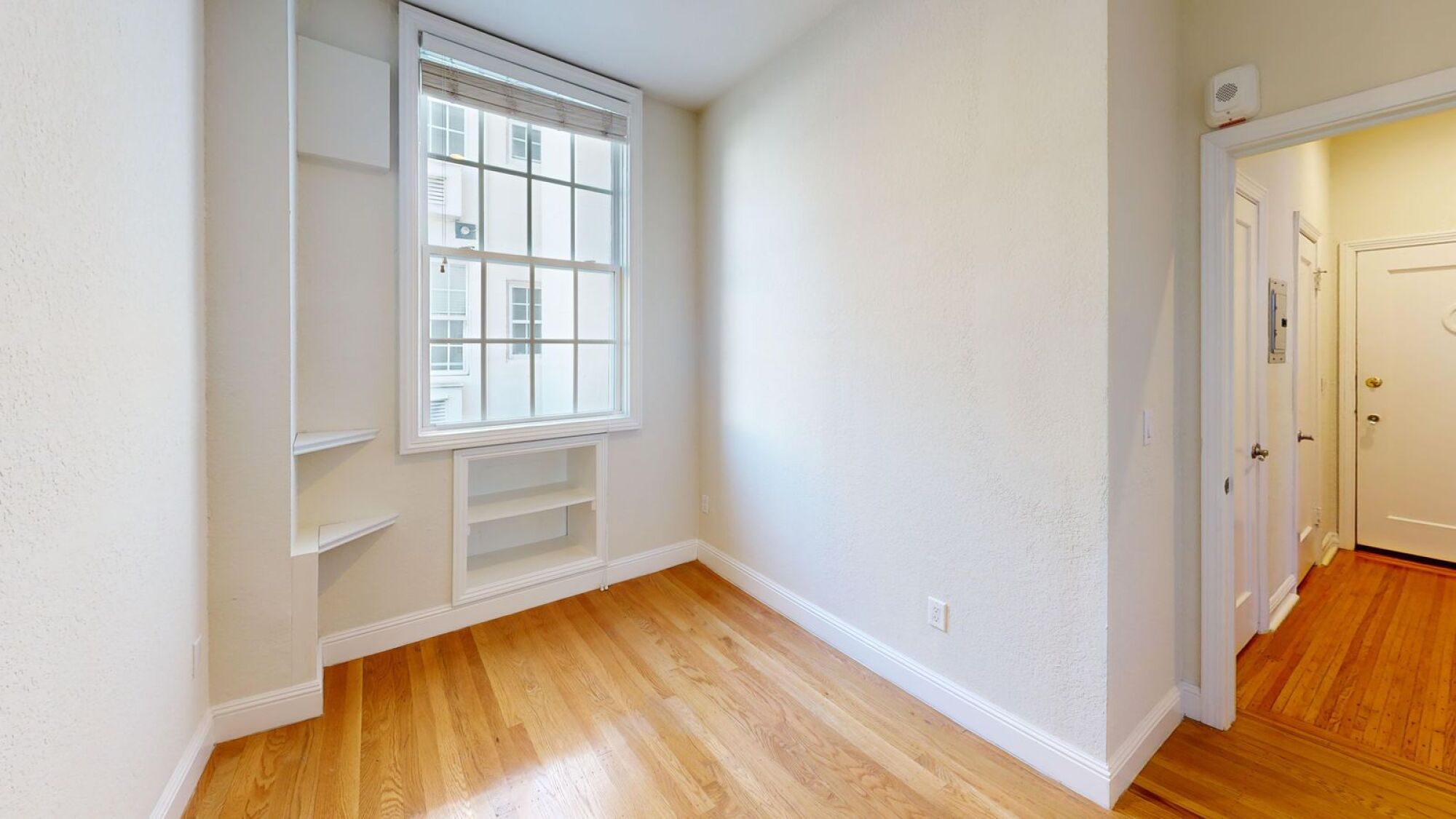 A room with a window and wooden floors.