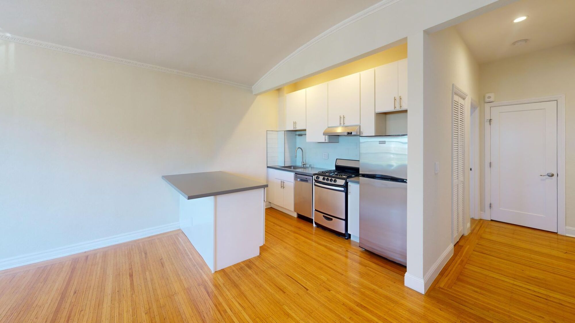 A kitchen with white cabinets and a wooden floor.
