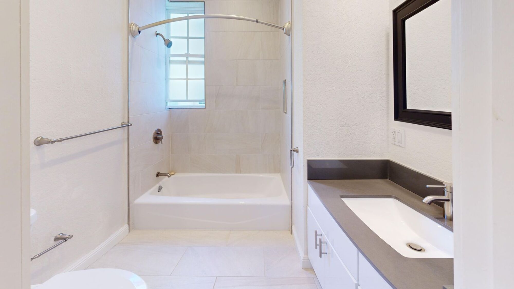 A white bathroom with a tub, sink, and mirror.