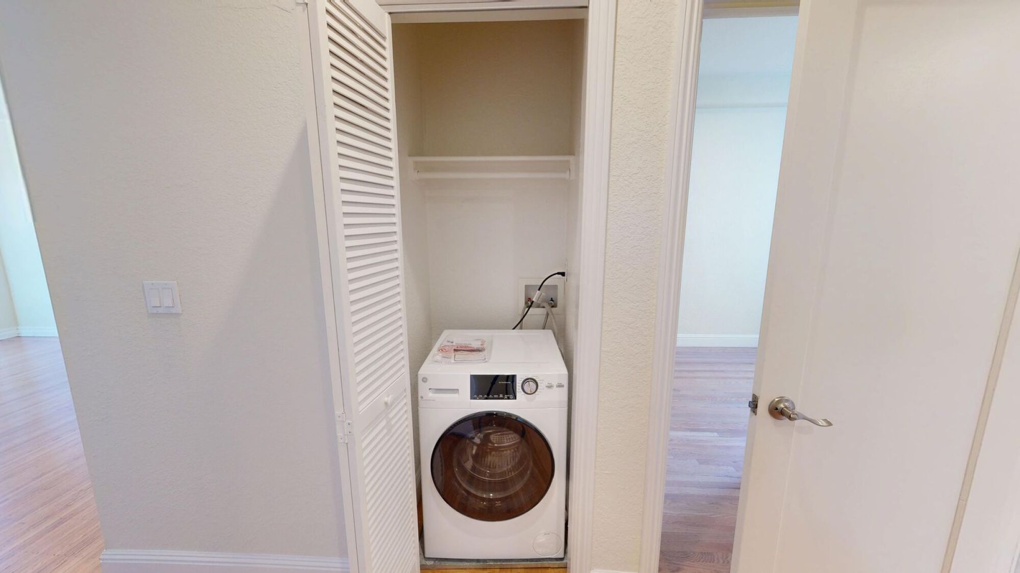 A white dryer is in a small closet.