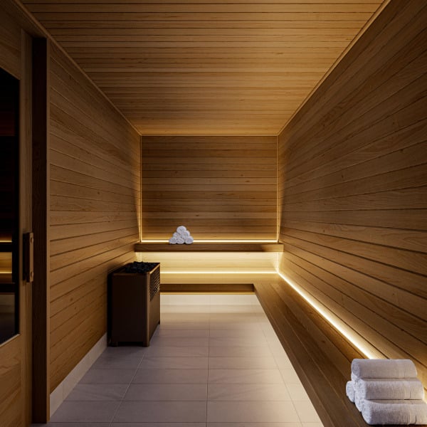 Modern wooden sauna room with folded white towels, benches, and soft ambient lighting.