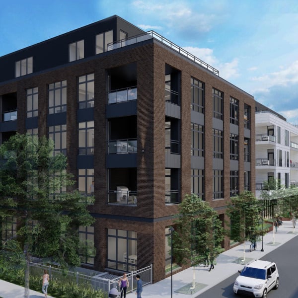 Modern apartment building with large windows, balconies, and trees along a city sidewalk on a sunny day.