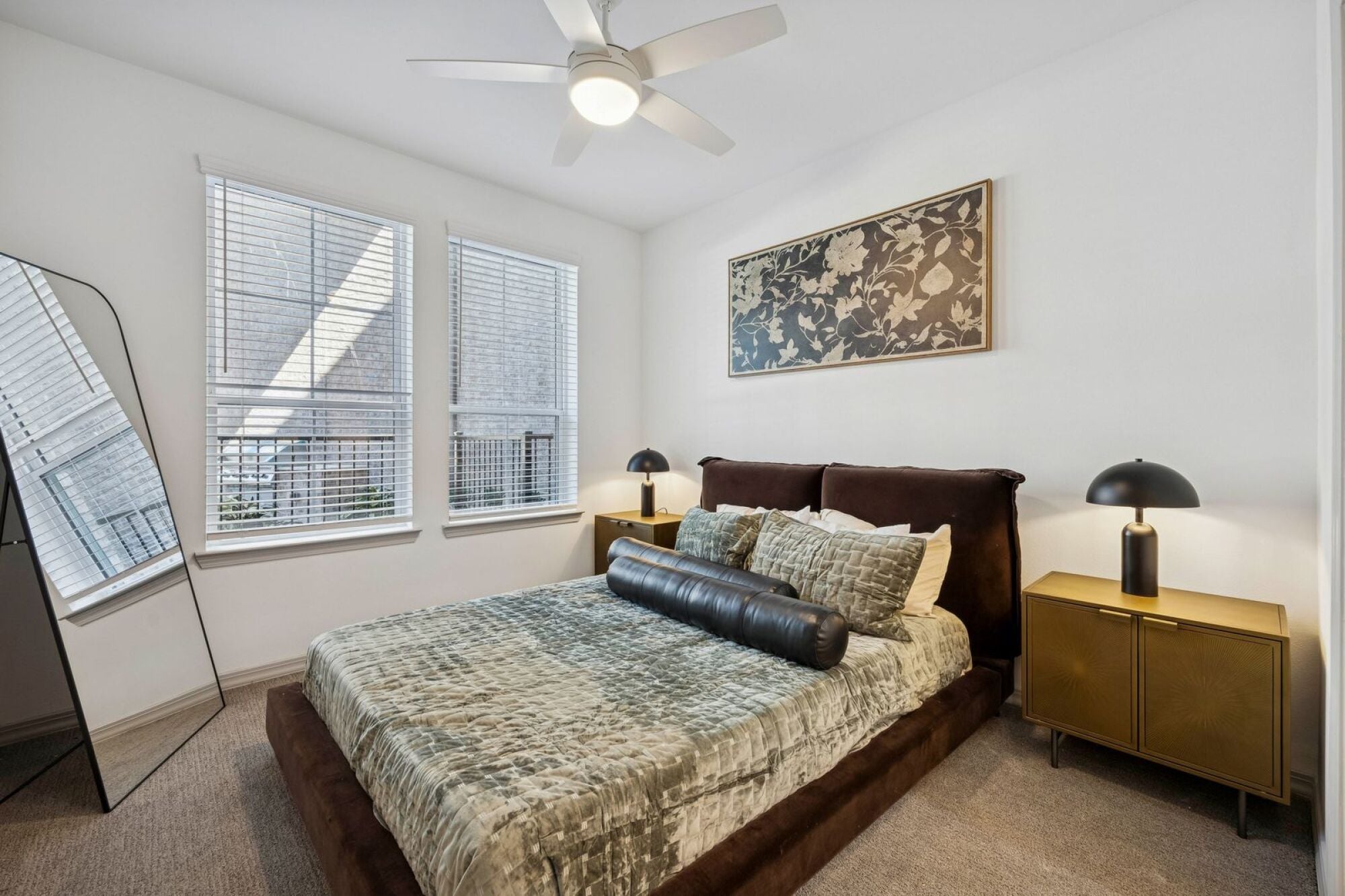 A carpeted bedroom with a ceiling fan at The Elara in Farmers Branch, Texas.