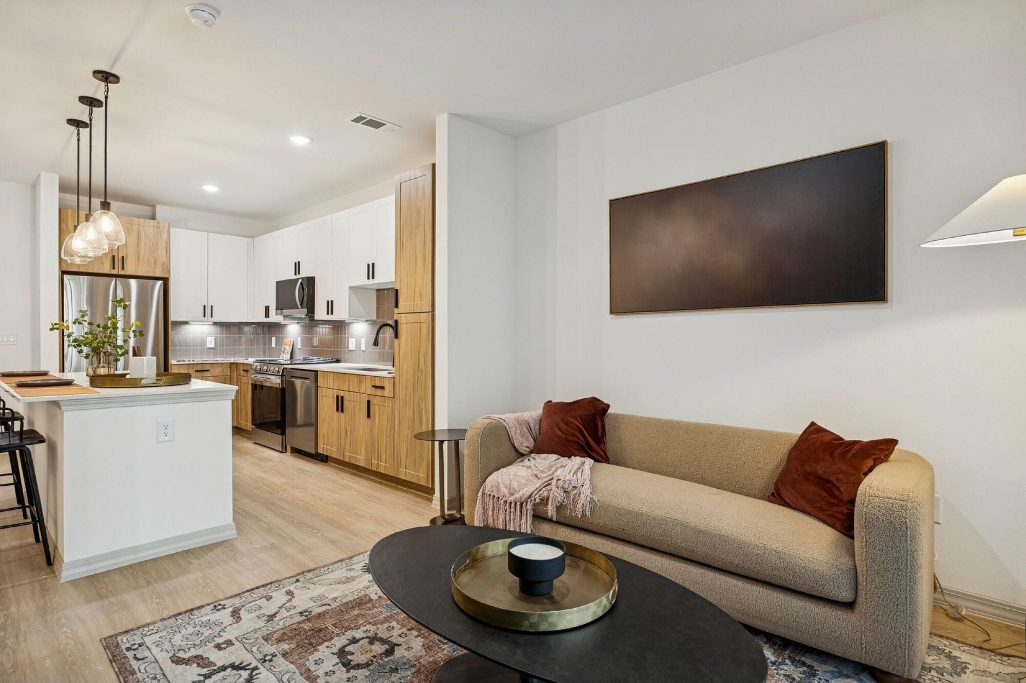 Stylish kitchen and living room at The Elara Apartments in Farmers Branch, TX