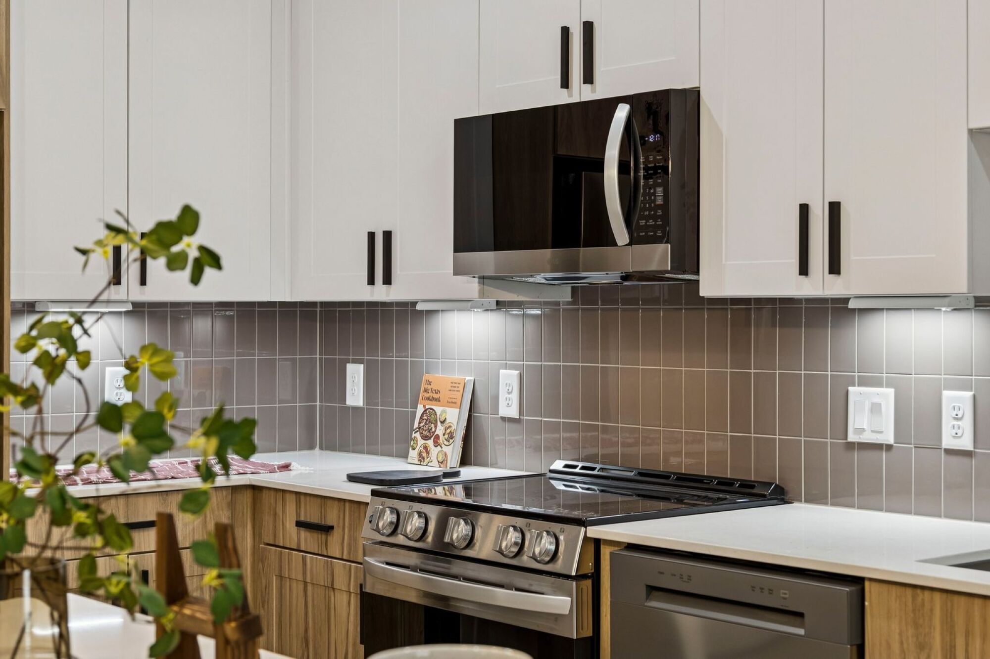 Bright modern kitchen at The Elara in Farmers Branch, TX featuring quartz-style countertops and stainless steel appliances near Dallas