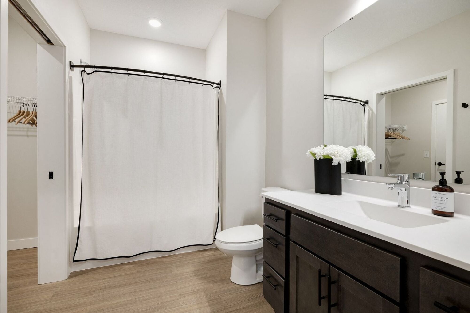 A bathroom with a white shower curtain and a white toilet at The Blakeley in Shakopee, MN.