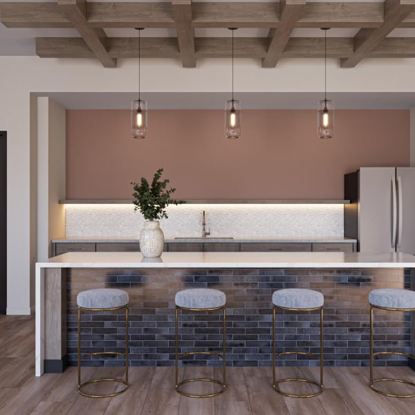 Modern kitchen with a marble island, four stools, pendant lights, and a vase with greenery on the counter.