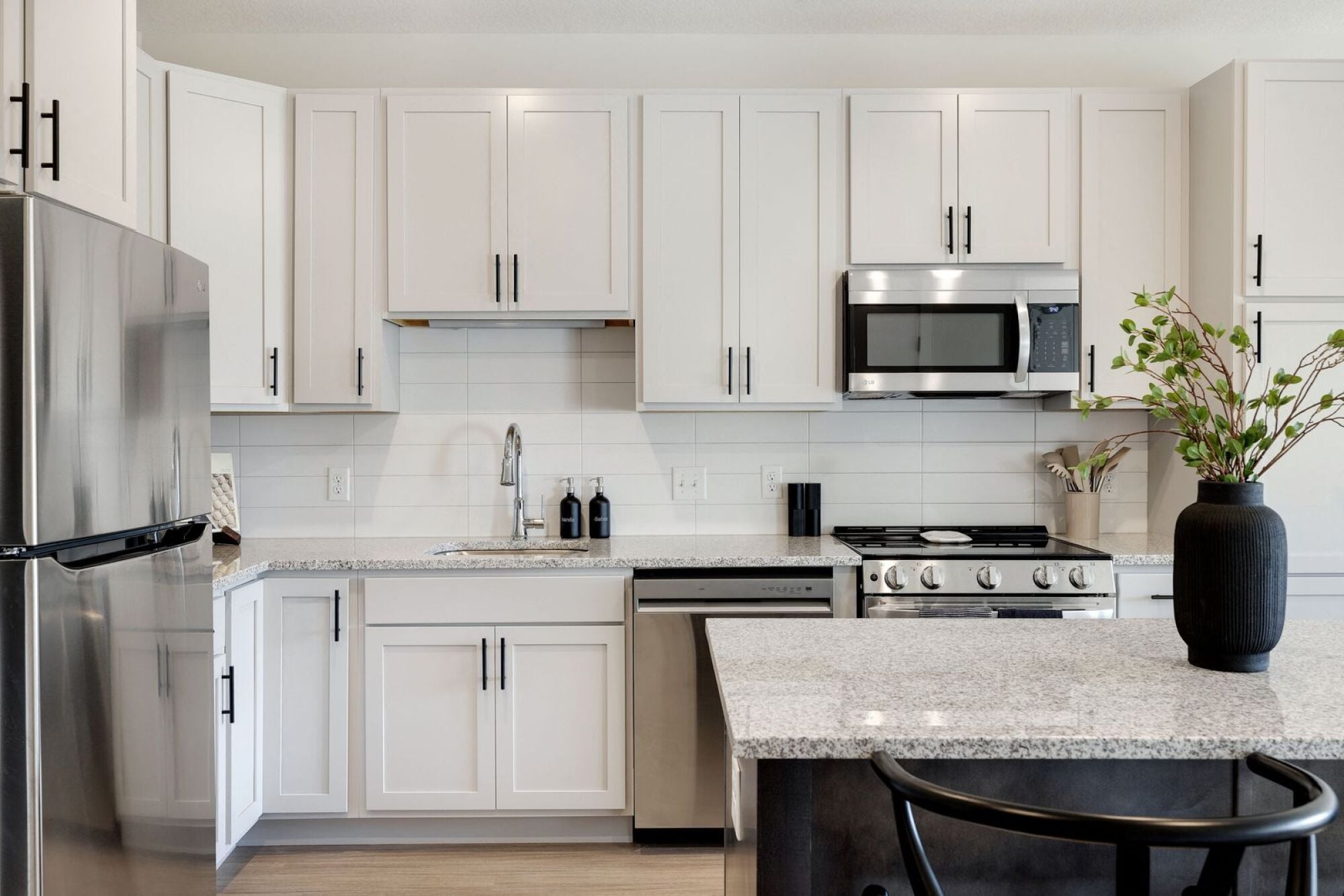 A kitchen with white cabinets and a granite countertop at The Blakeley in Shakopee, MN.
