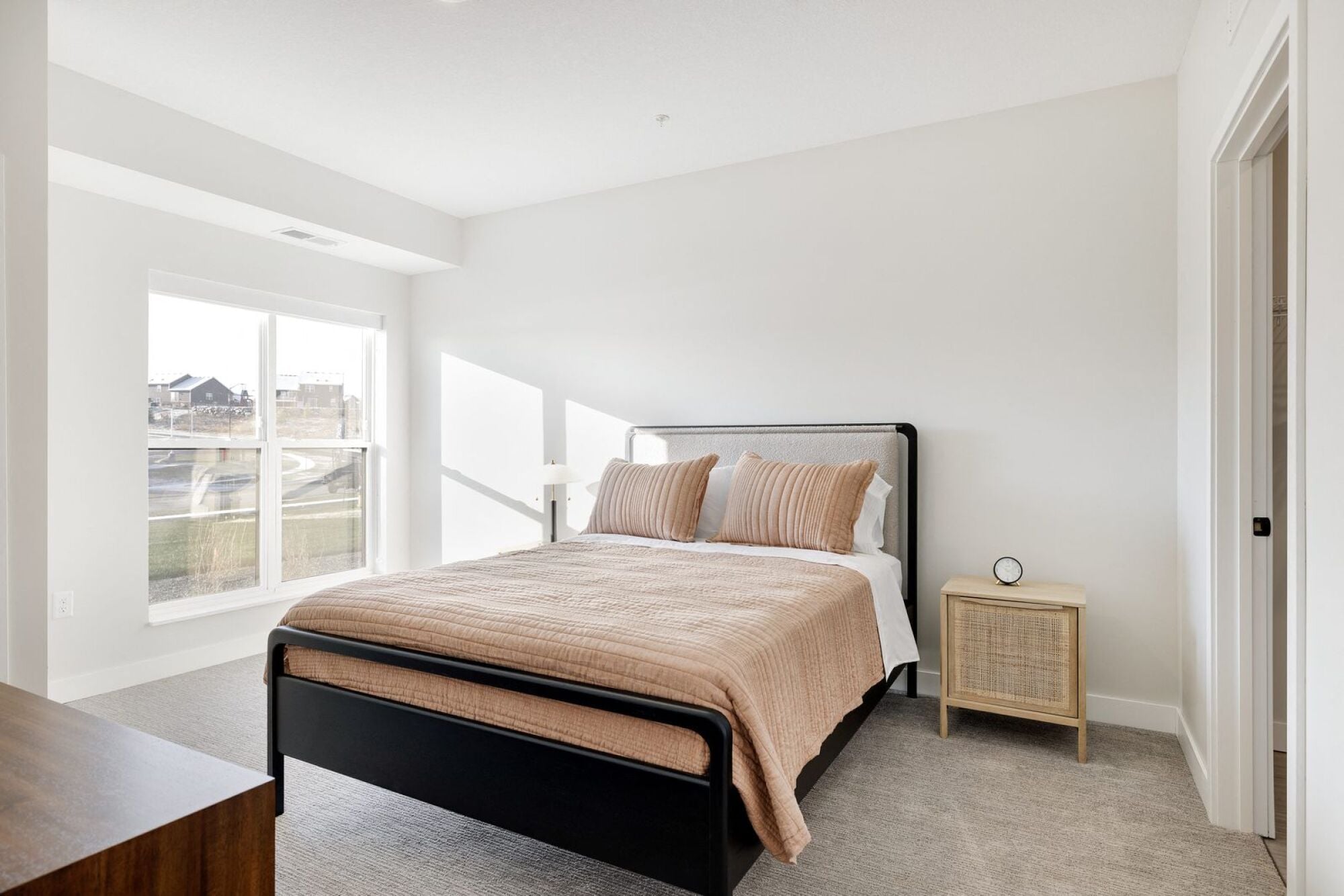 A bedroom with a large bed and a window overlooking a street at The Blakeley in Shakopee, MN.