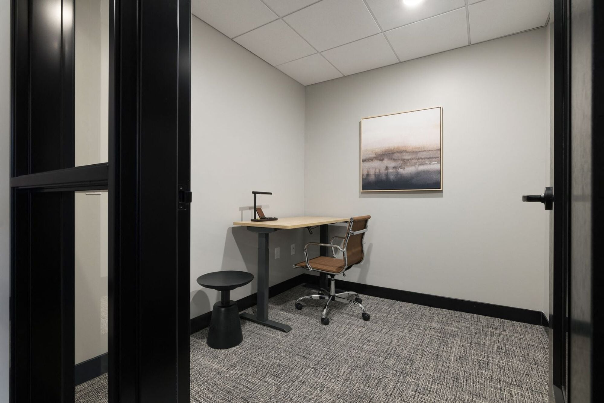 A room with a desk, chair, and a painting on the wall at The Blakeley in Shakopee, MN.