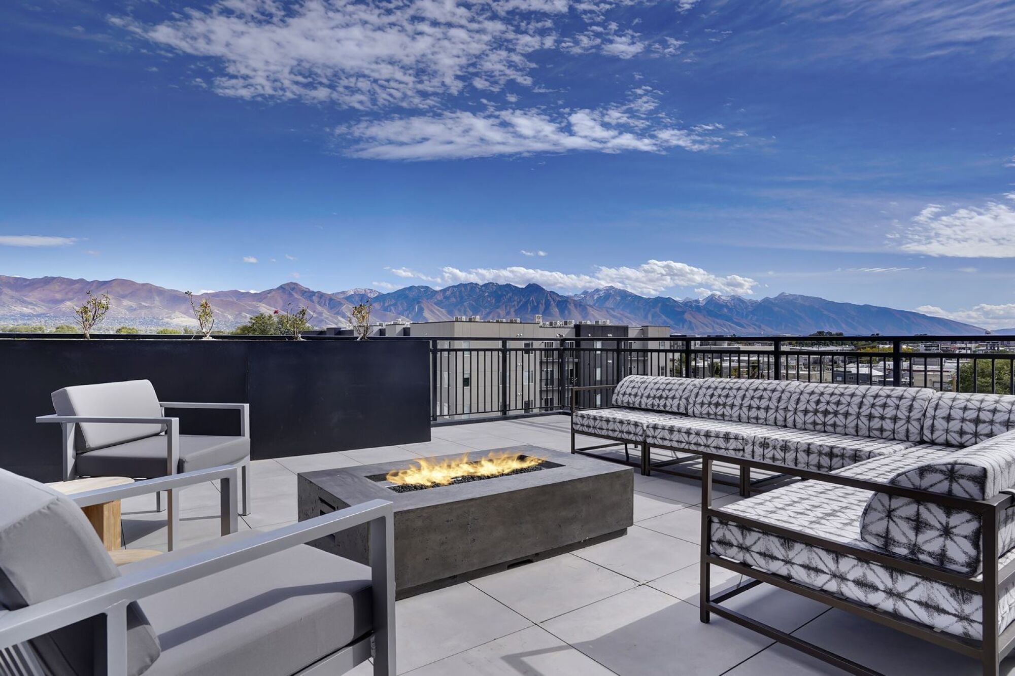 A patio with a fire pit and seating area overlooking a mountain range at The Whitney in Salt Lake City, Utah.