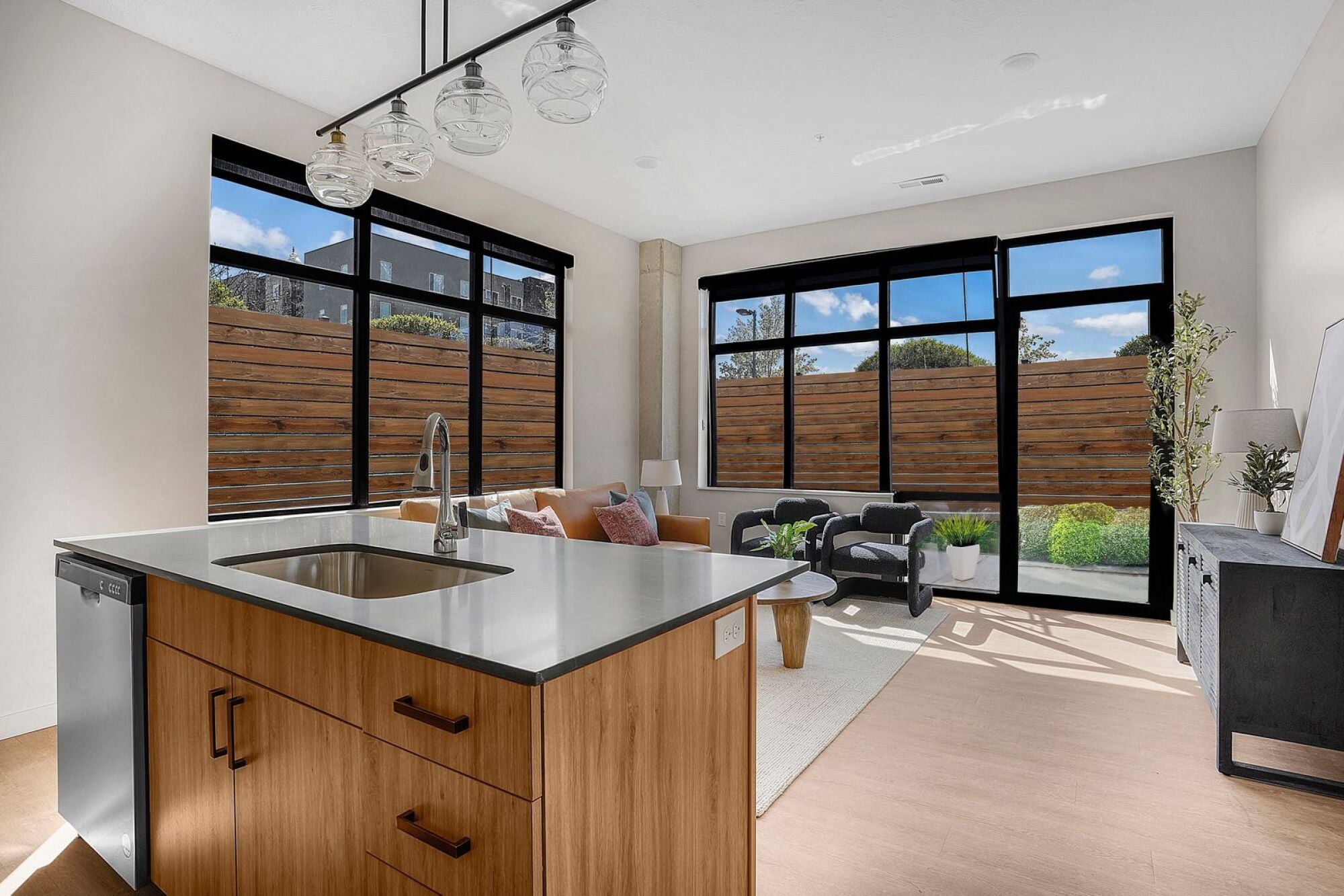 A modern kitchen with wooden cabinets and a stainless steel sink at The Whitney in Salt Lake City, Utah.