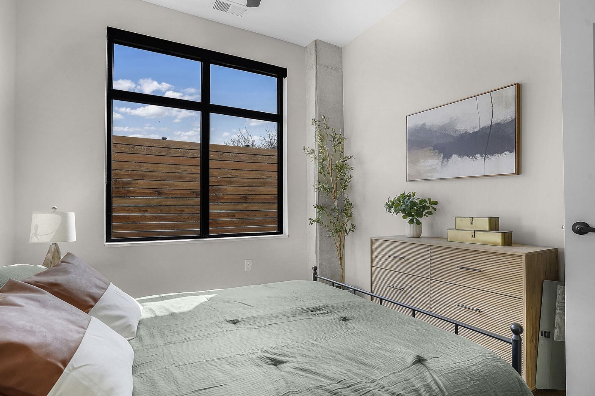 A bedroom with a large bed and a painting on the wall at The Whitney in Salt Lake City, Utah.