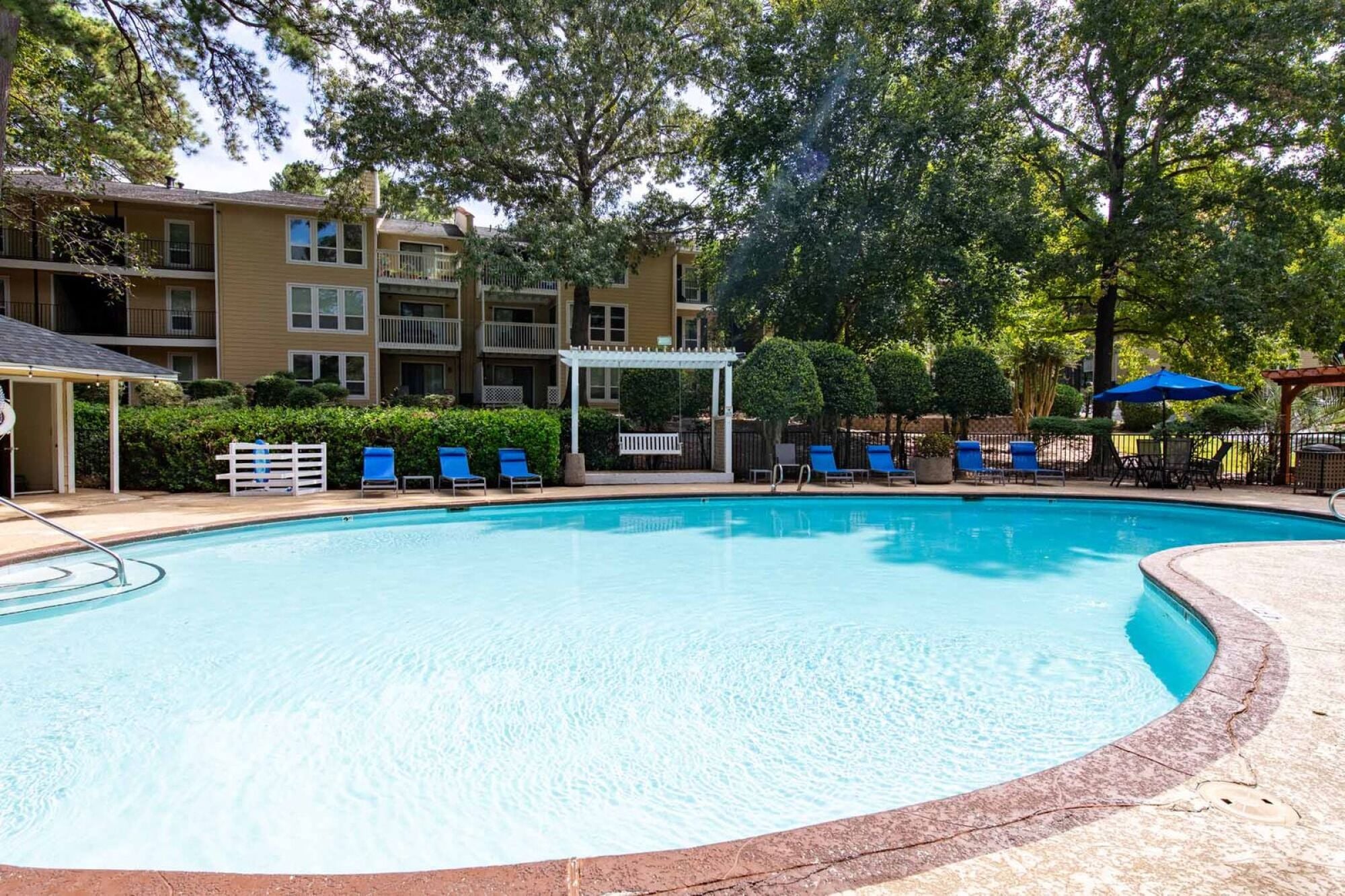 A swimming pool surrounded by trees and apartment buildings.