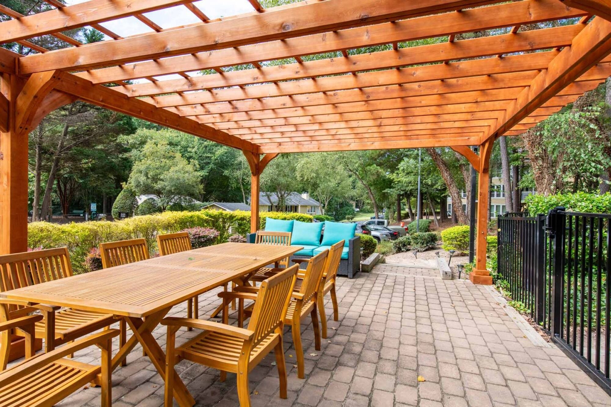 A wooden patio with a table and chairs under a pergola.
