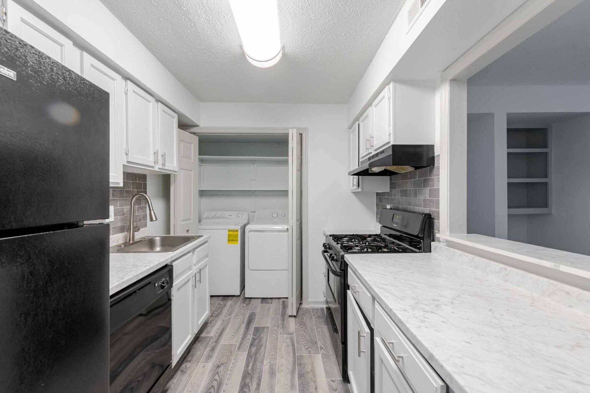A kitchen with black appliances and white cabinets.